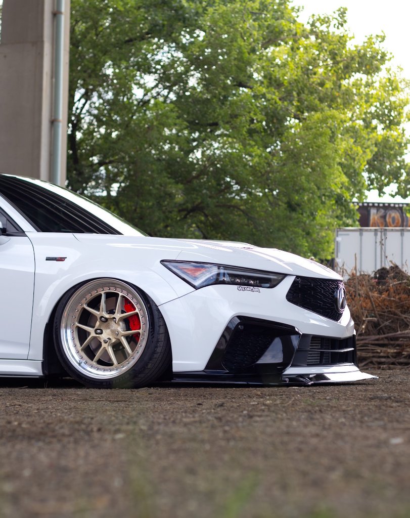 Close-up of white Acura with gold multi-spoke wheels and red brake caliper
