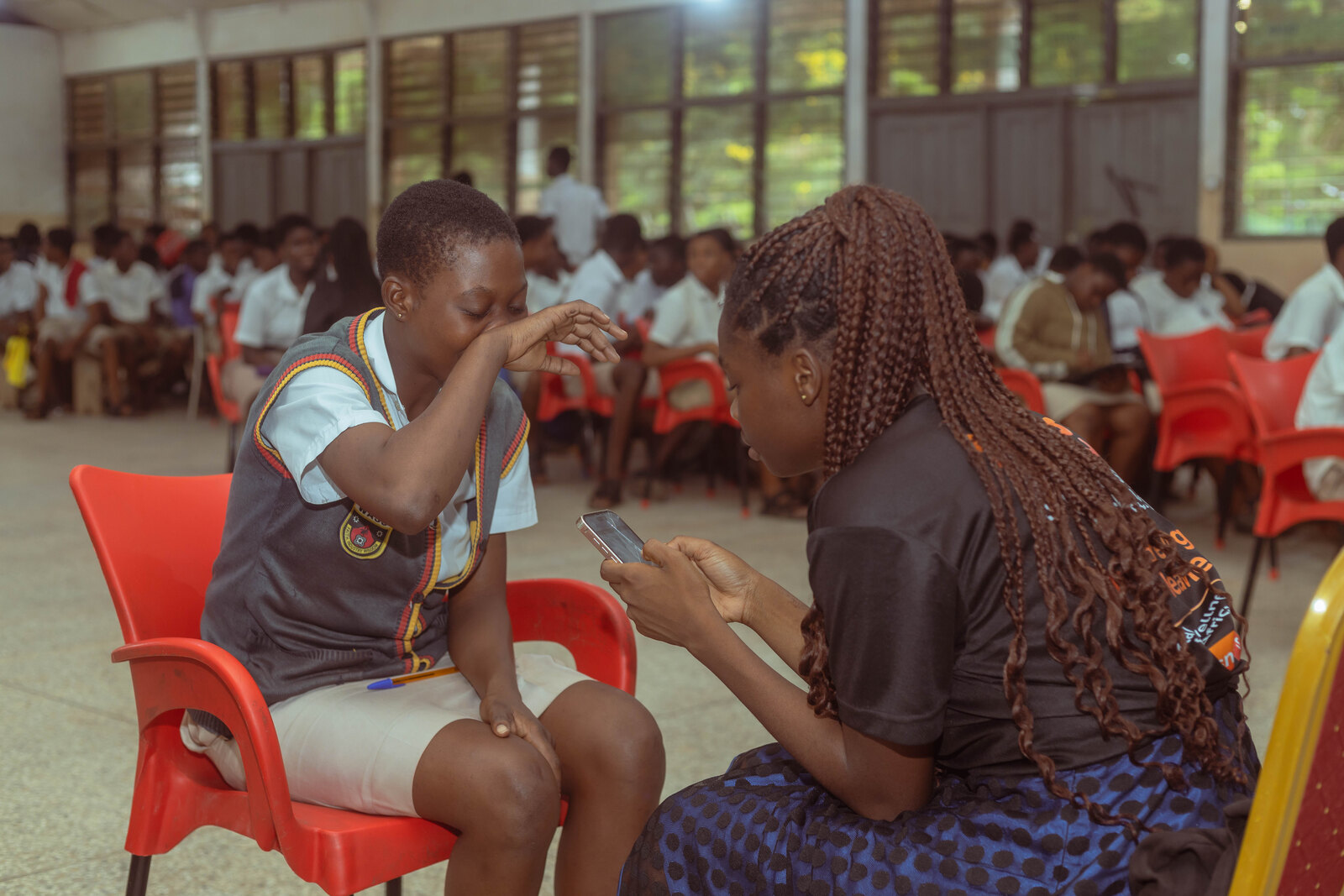A community mental health officer screening a young student in a school hall in Ghana