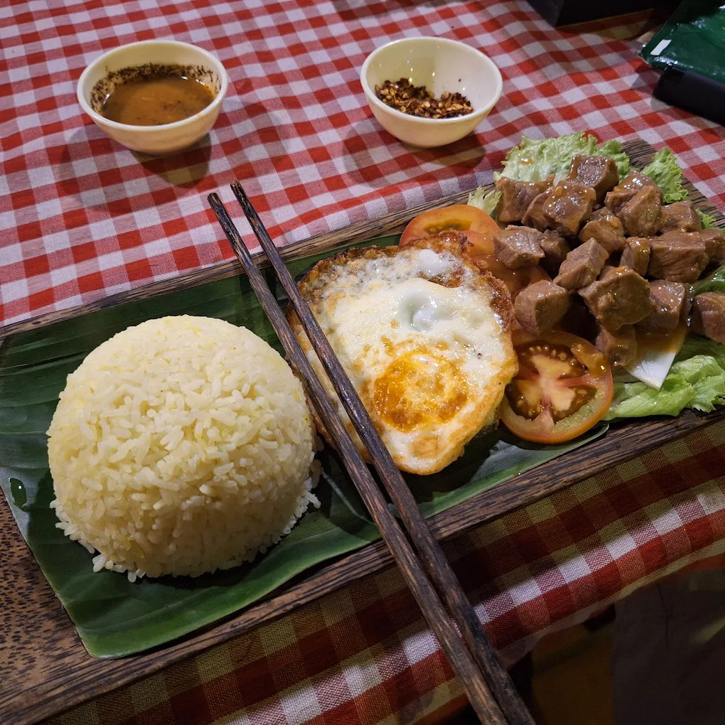 Traditional Lok Lak beef dish with rice and fresh vegetables served on banana leaf