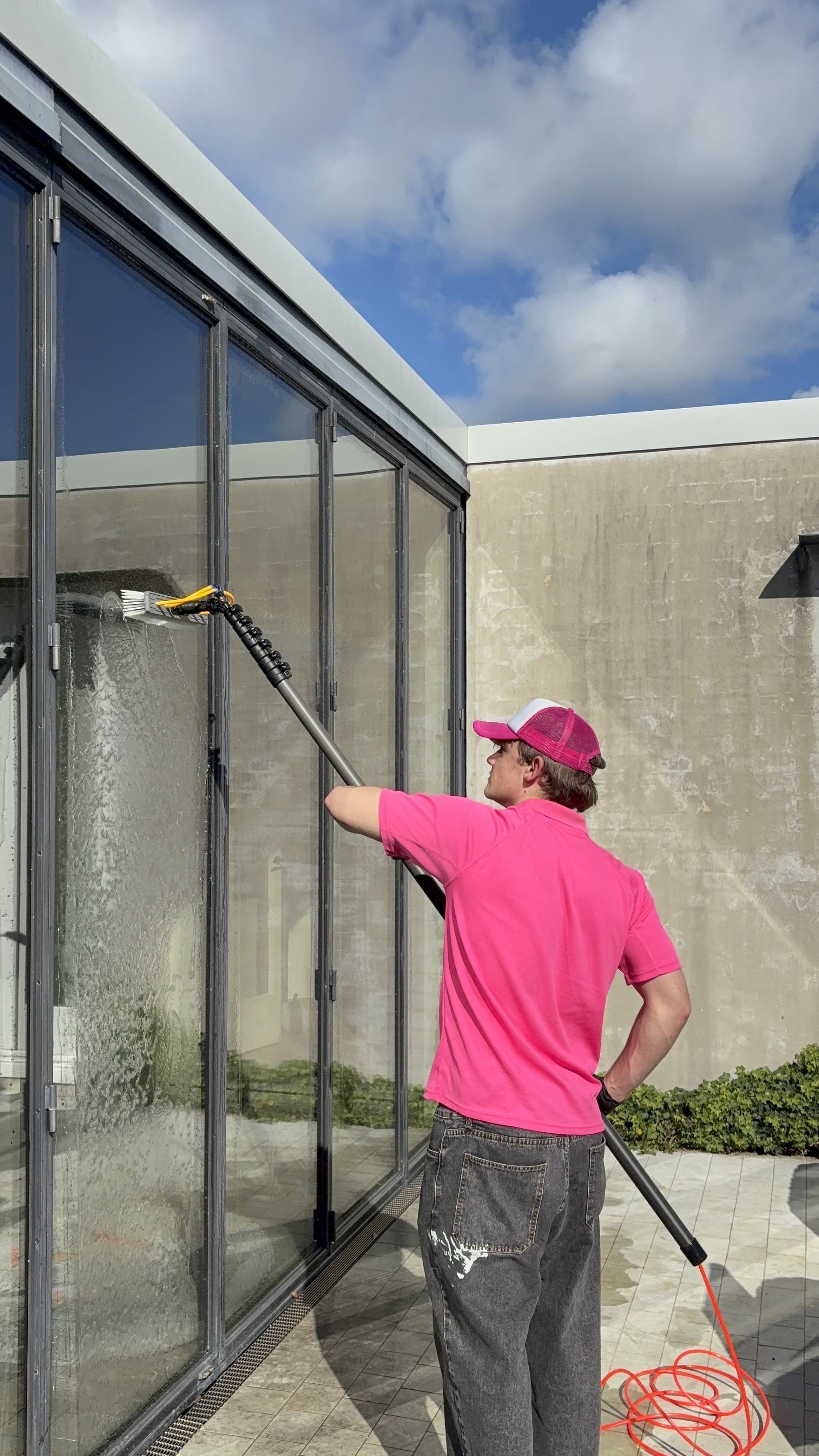 Altra team member cleaning glass panels with a water-fed pole