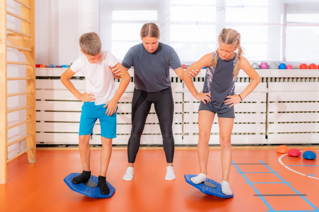 Kinder trainieren Koordination auf Balancebrettern mit Trainerin