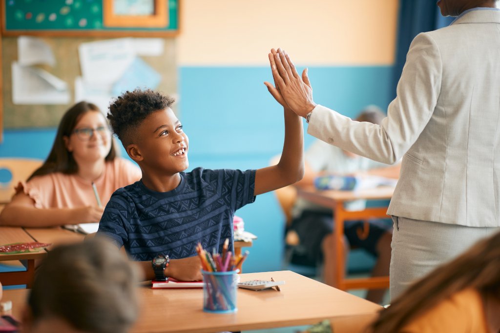 Schüler gibt seinem Lehrer einen High-Five im Unterricht