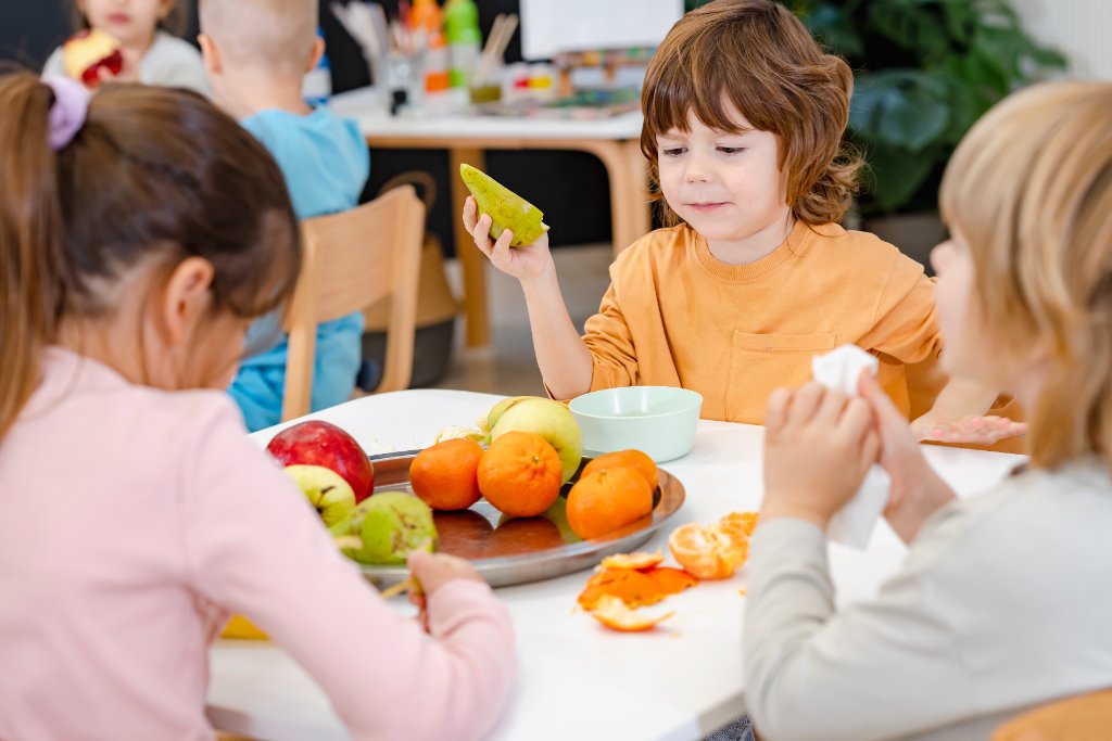 Kinder essen gemeinsam Obst in der Kita