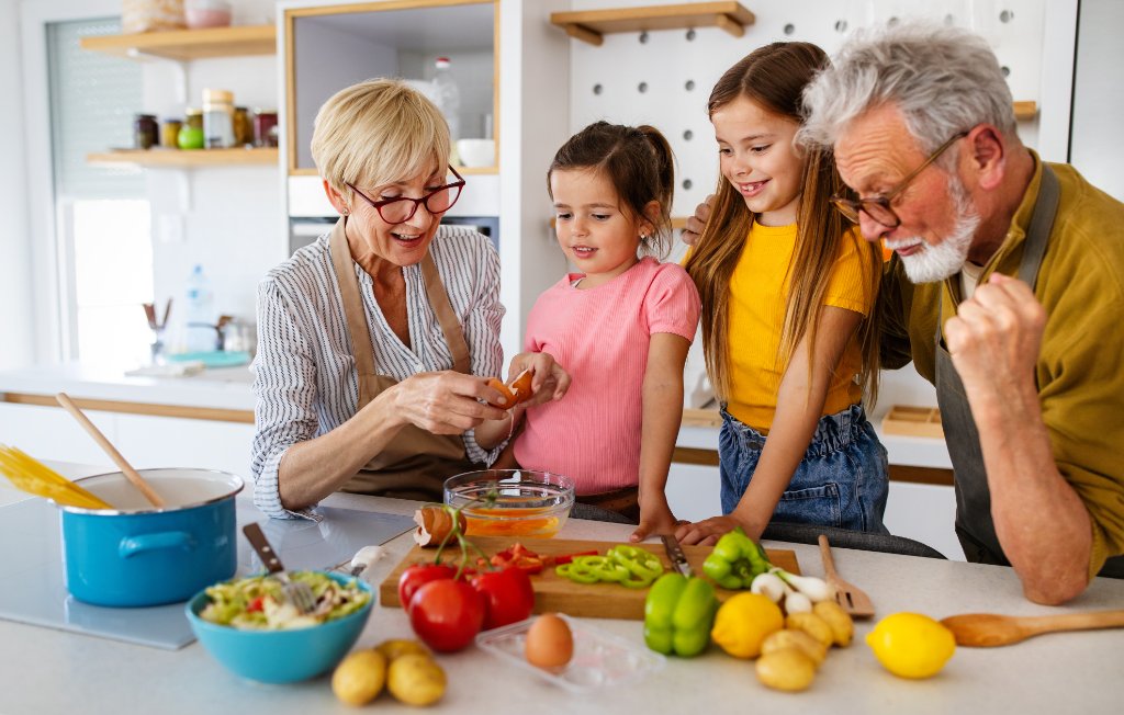 Großeltern kochen gemeinsam mit Enkeln in der Küche