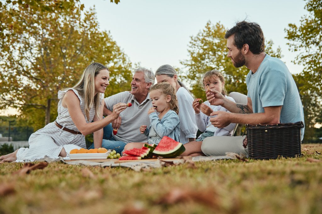 Familie beim Picknick im Park mit Obst und Wassermelone