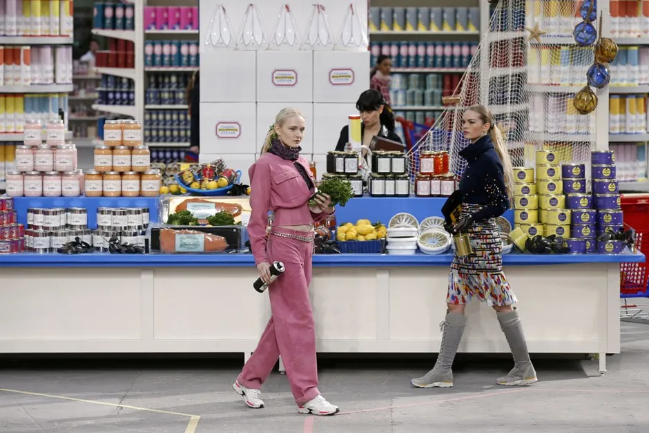 Models walk between aisles of Chanel-branded products inside the supermarket set