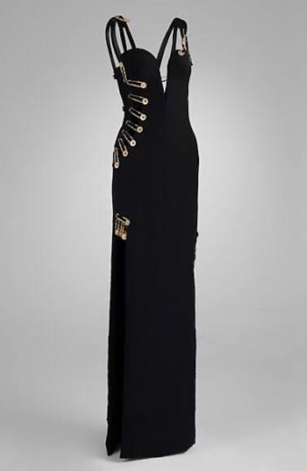Gianni Versace's 1994 black safety-pin evening dress, with oversized gold-tone safety pins securing the plunging neckline, displayed on a mannequin.