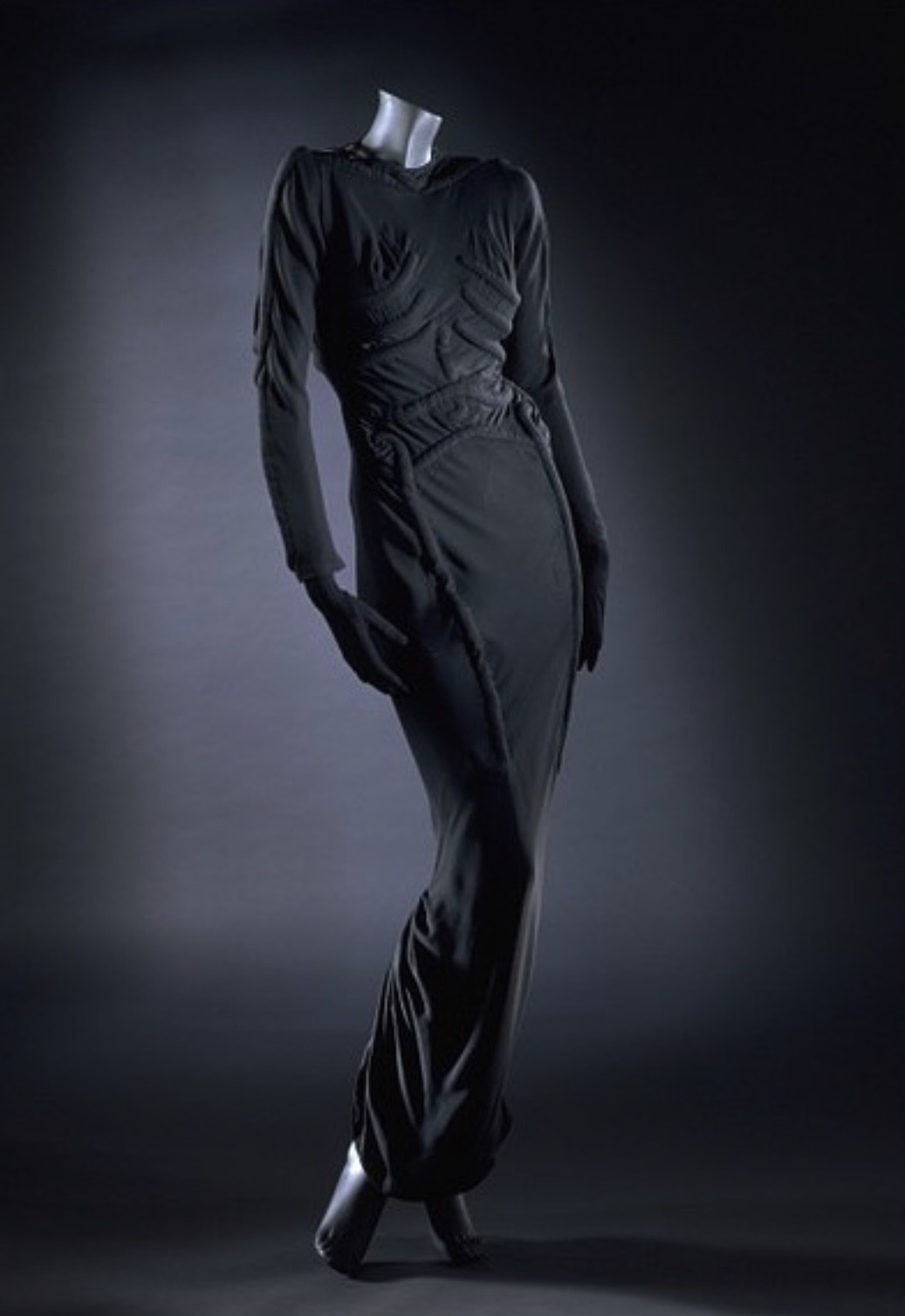 Elsa Schiaparelli's Skeleton Dress of 1938, a black floor-length gown with padded trapunto quilting tracing a human ribcage and spine, displayed on a mannequin.