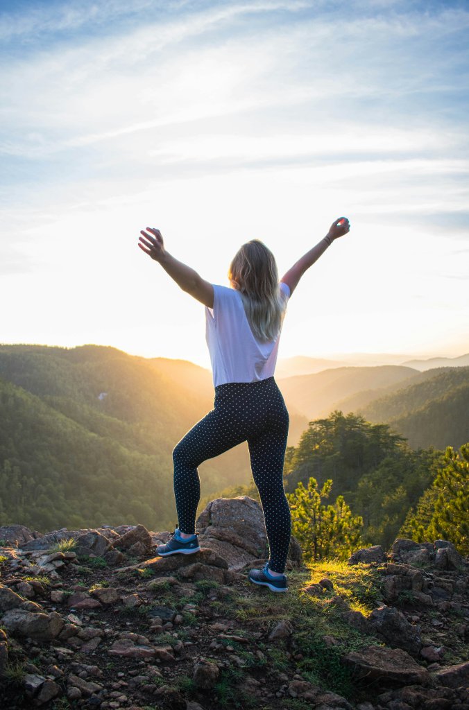 Woman standing on a mountain peak with arms outstretched