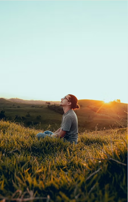 Man sitting in a field of tall grass looking toward the sky