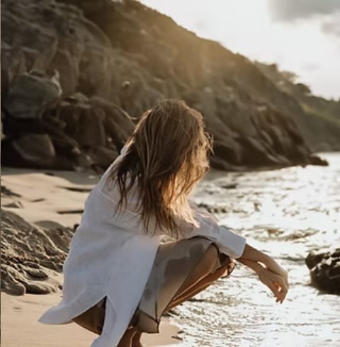 Woman crouching on a beach at golden hour