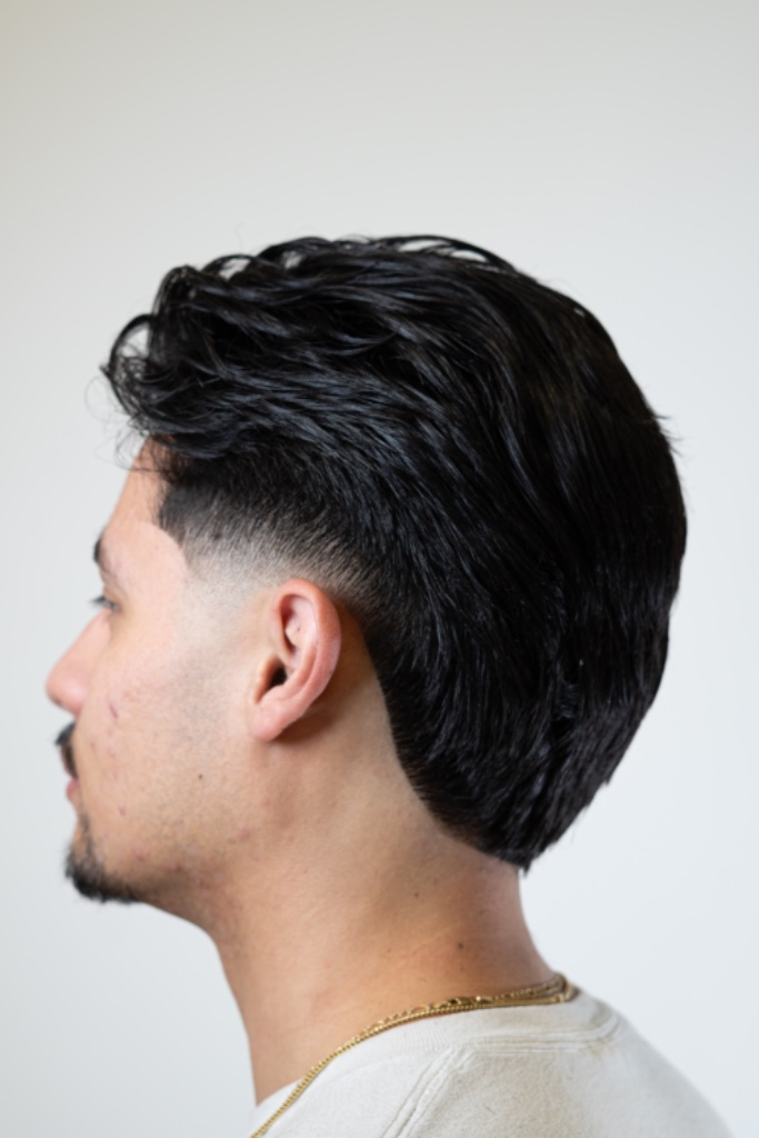 Profile portrait of a short textured taper fade against a light backdrop