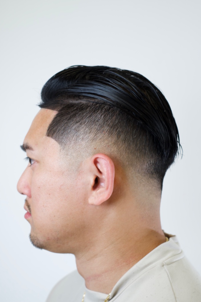 Profile view of a clean fade with combed-back top and mustache detail