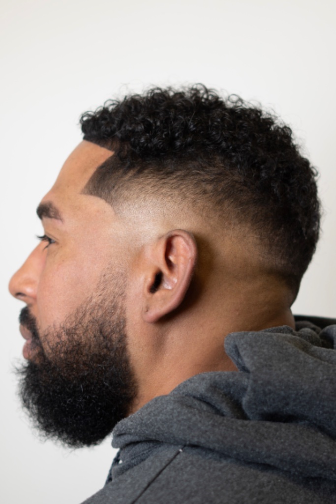 Curly-hair fade with a clean gradient transition and full groomed beard
