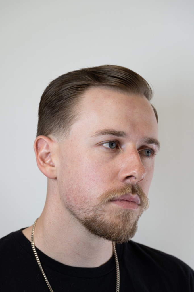 Swept-back top with a neatly trimmed light-brown beard and mustache