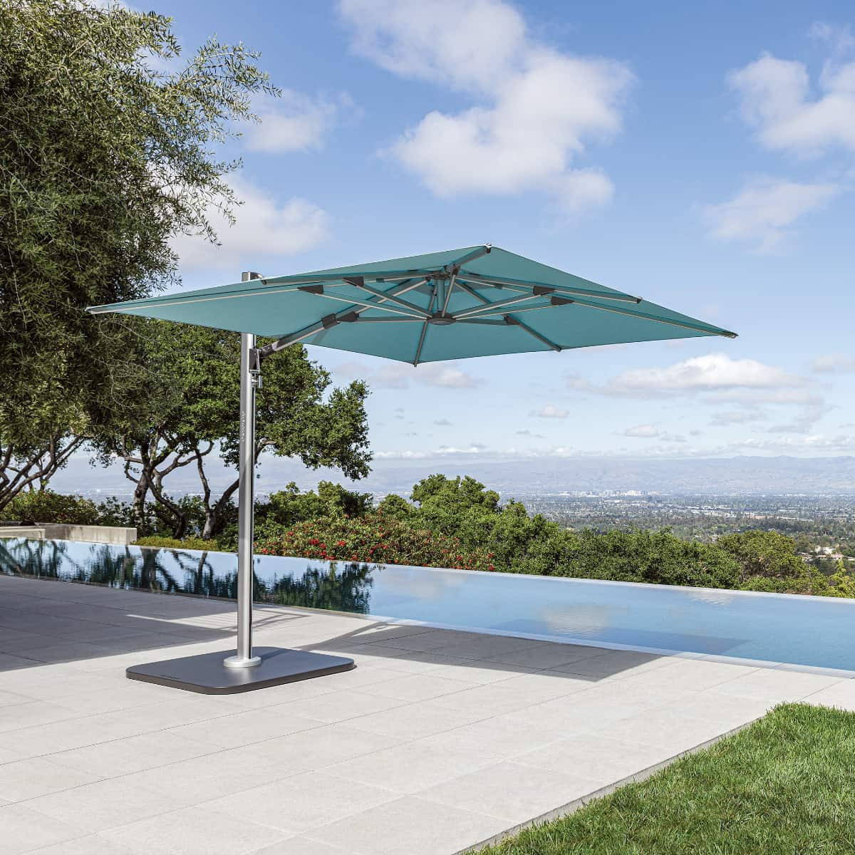 Sombrilla Shademaker Solaris de brazo lateral sobre terraza con alberca de borde infinito y vista a colinas