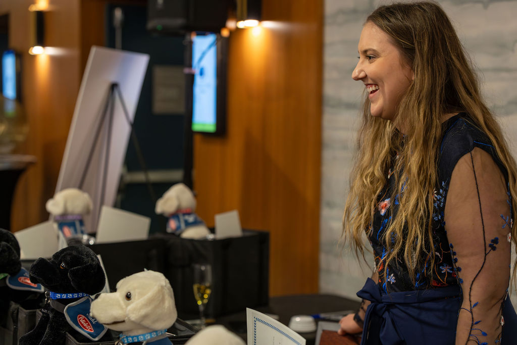 Gala 2025 volunteer smiling at registration with plush dogs