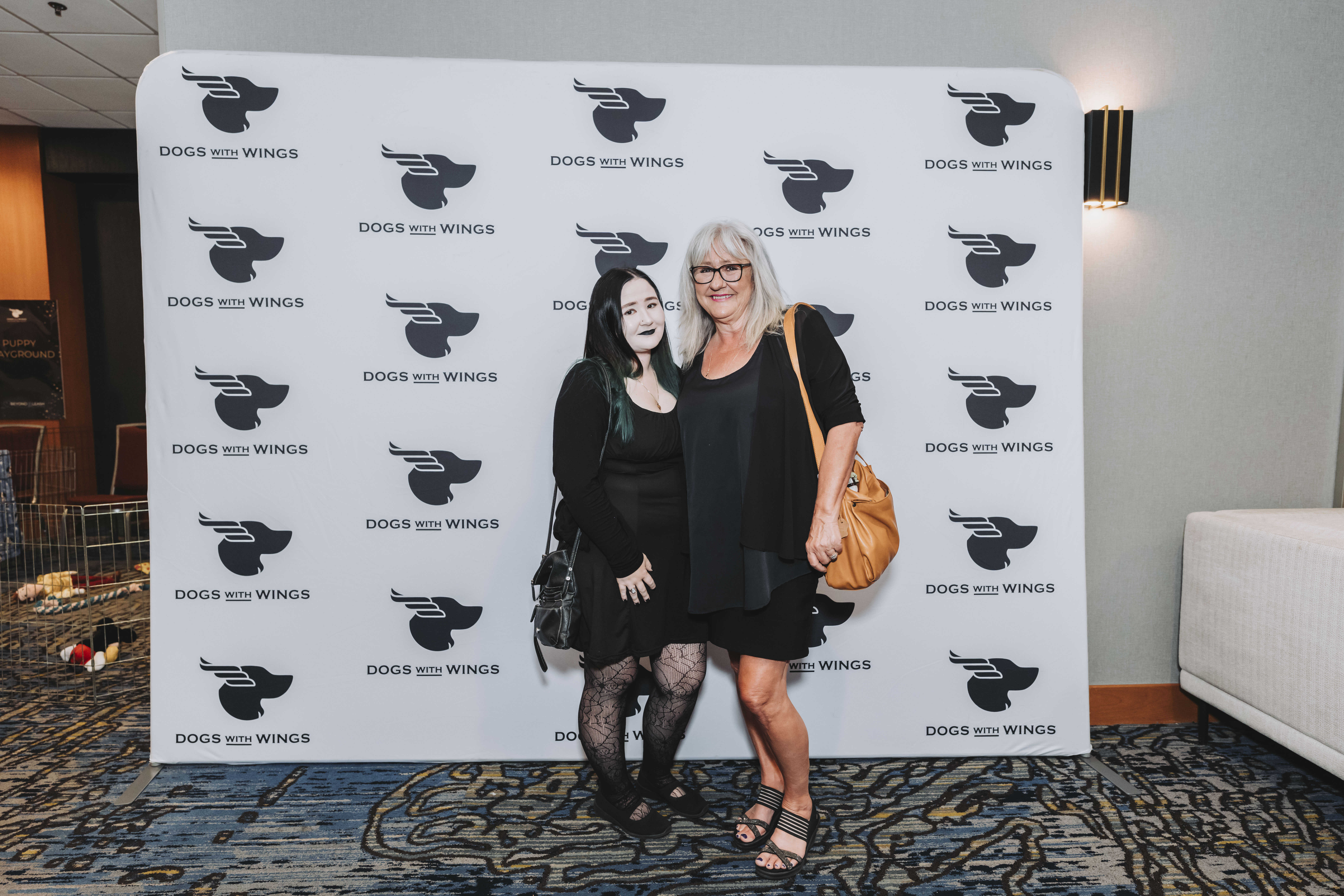 Two guests in black outfits posing at the photo wall