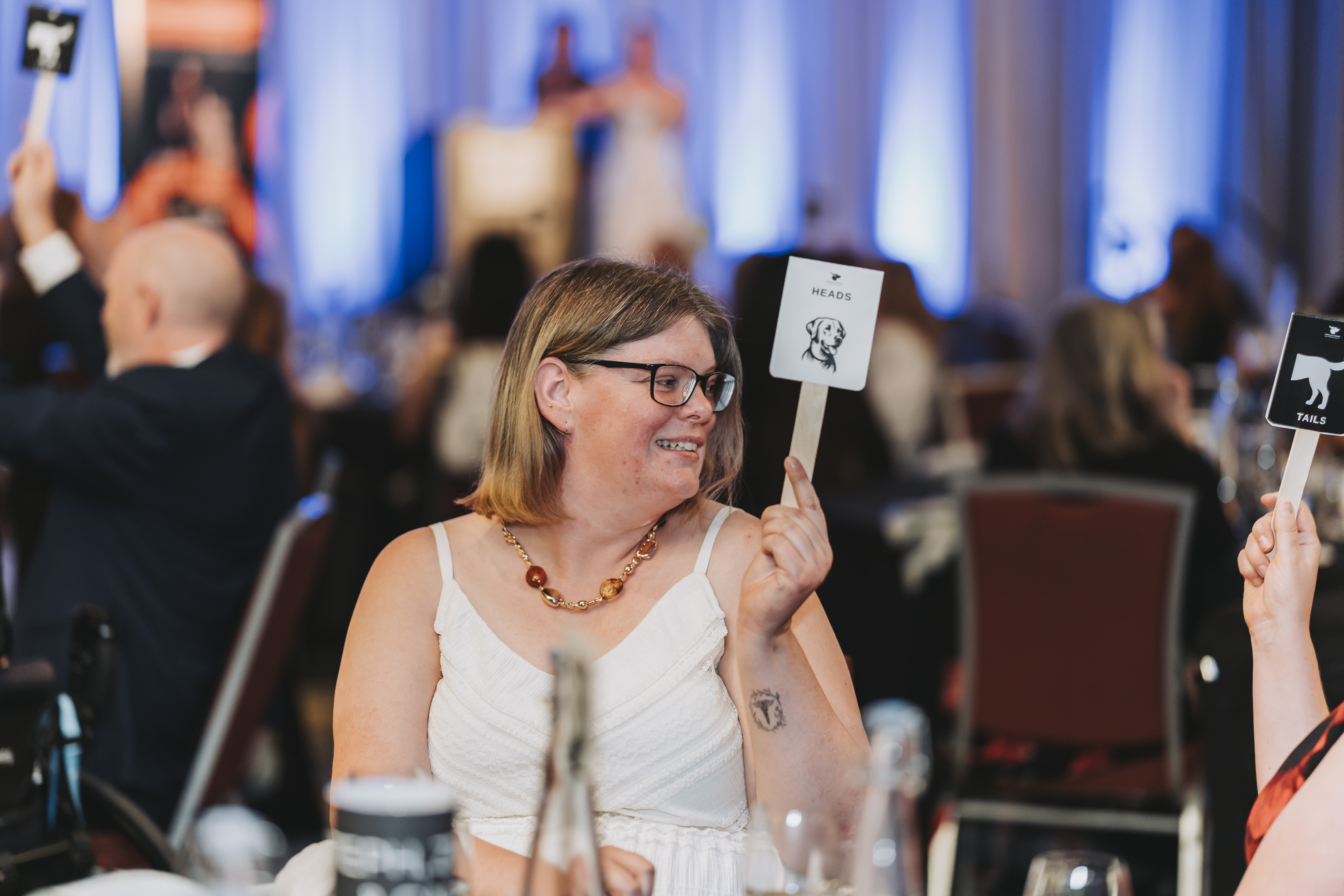 A guest raising a Heads paddle during the heads or tails game
