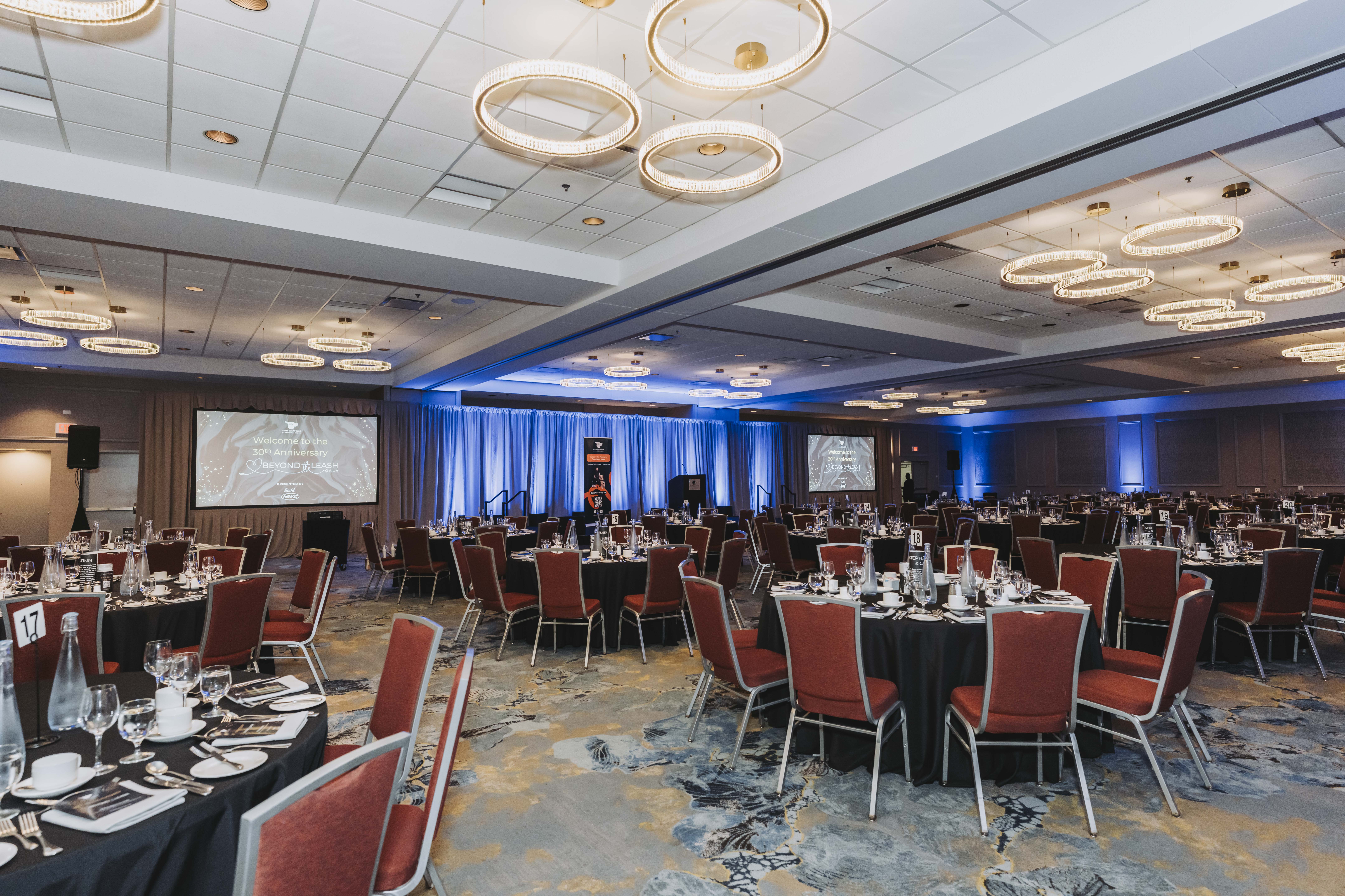 A wide view of the ballroom and stage screens welcoming guests