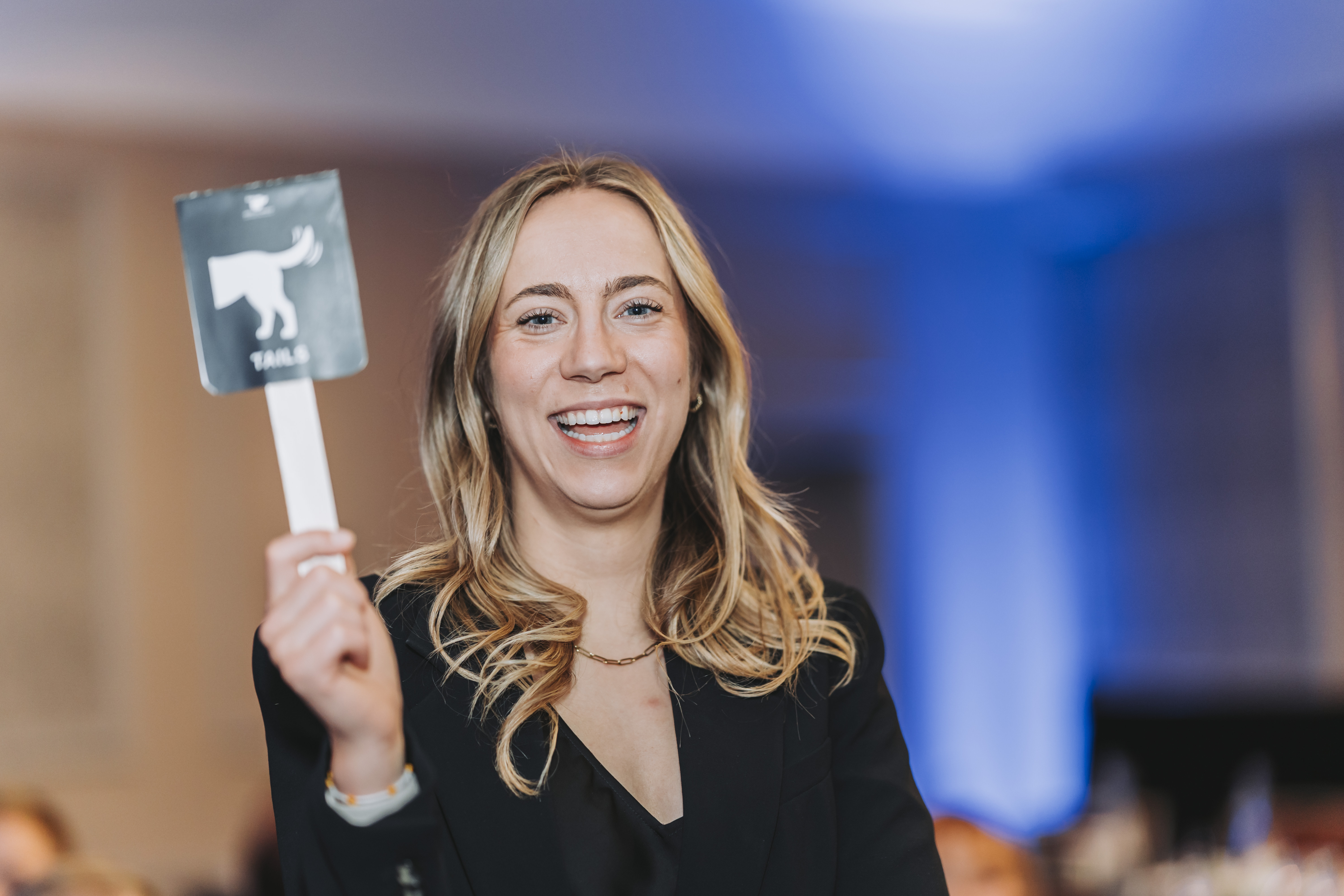 A smiling guest holding up a Tails paddle at the gala
