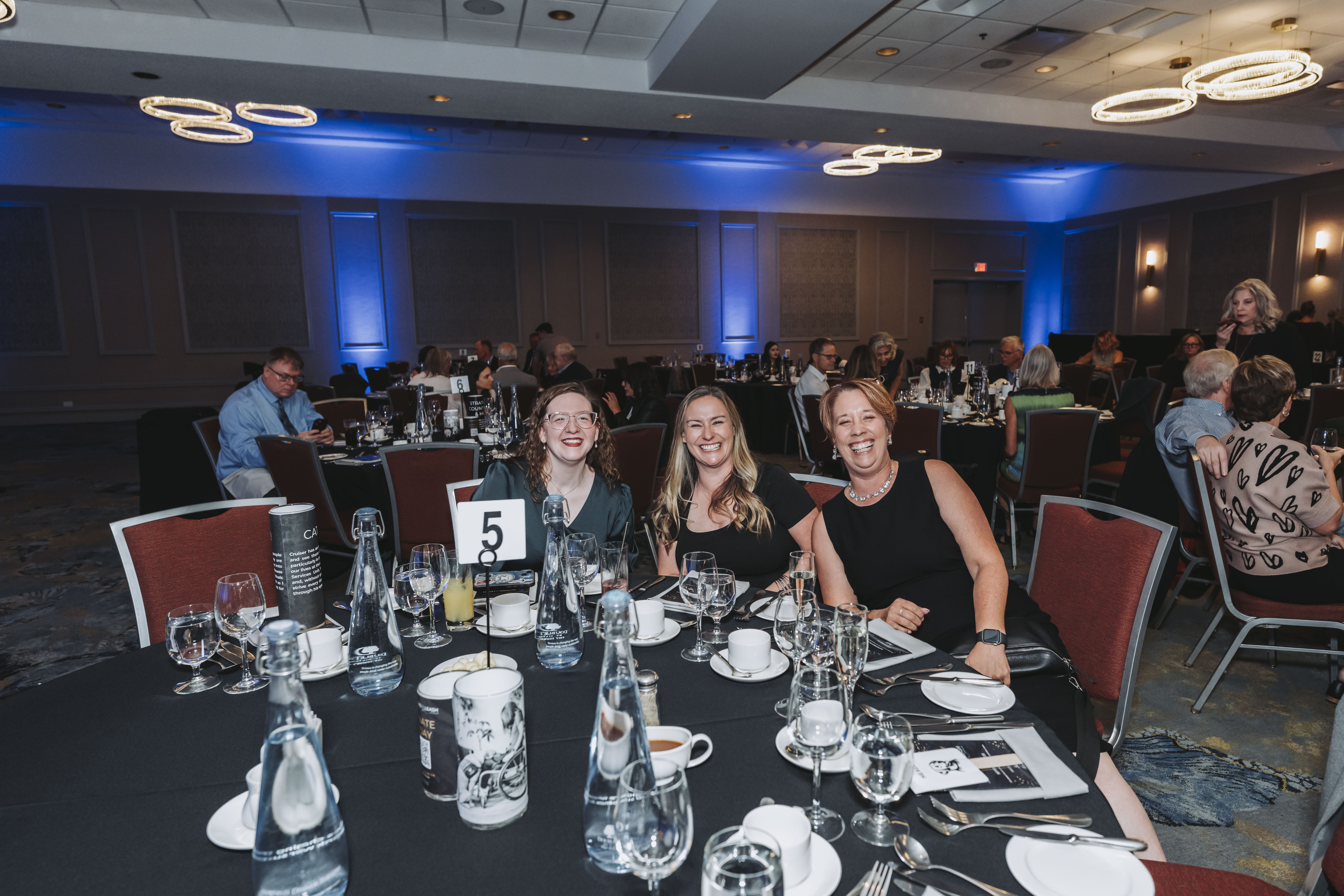 Three guests smiling together at table five