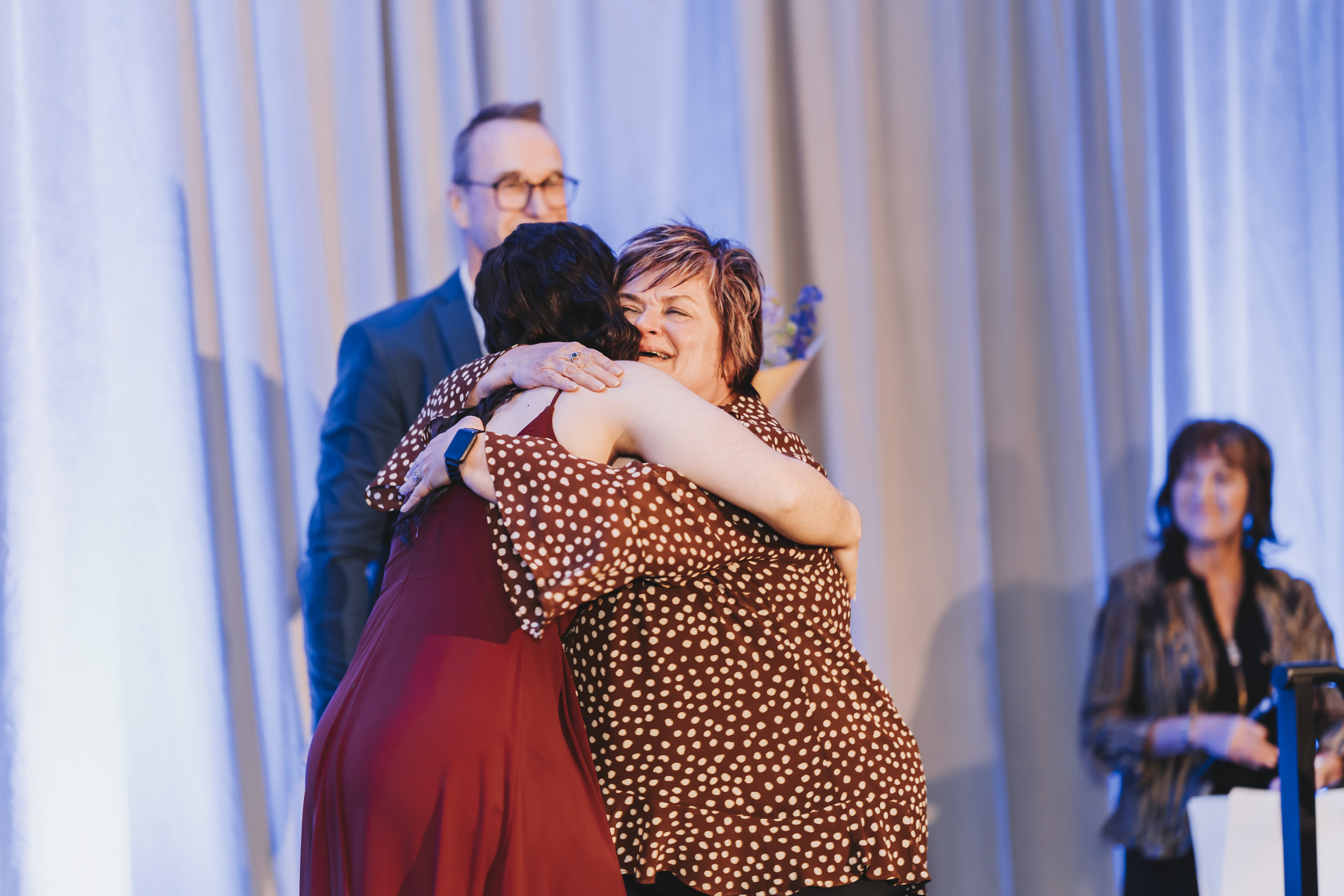 Two guests embracing on stage during the gala