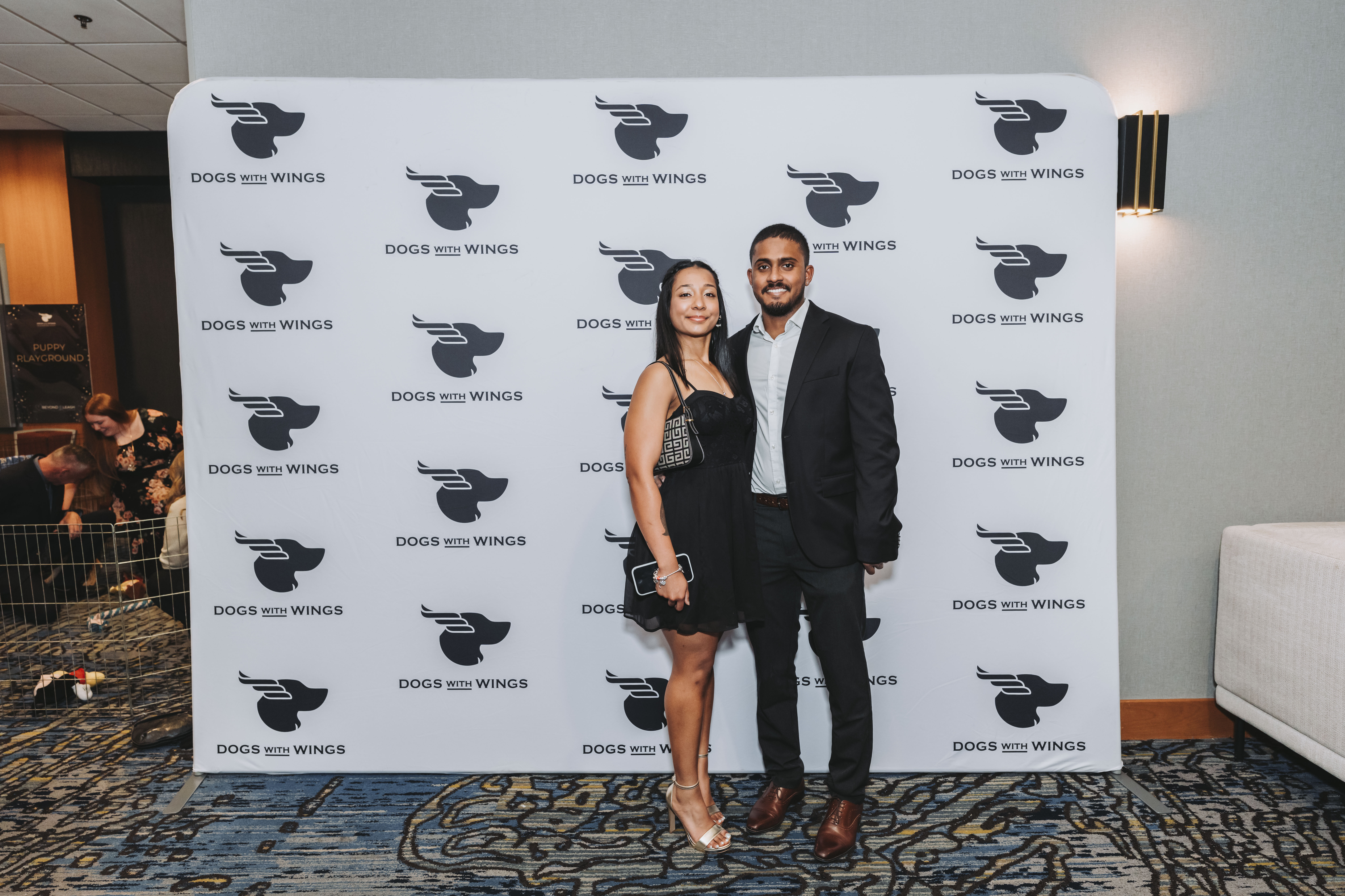 A couple in black posing at the gala step-and-repeat