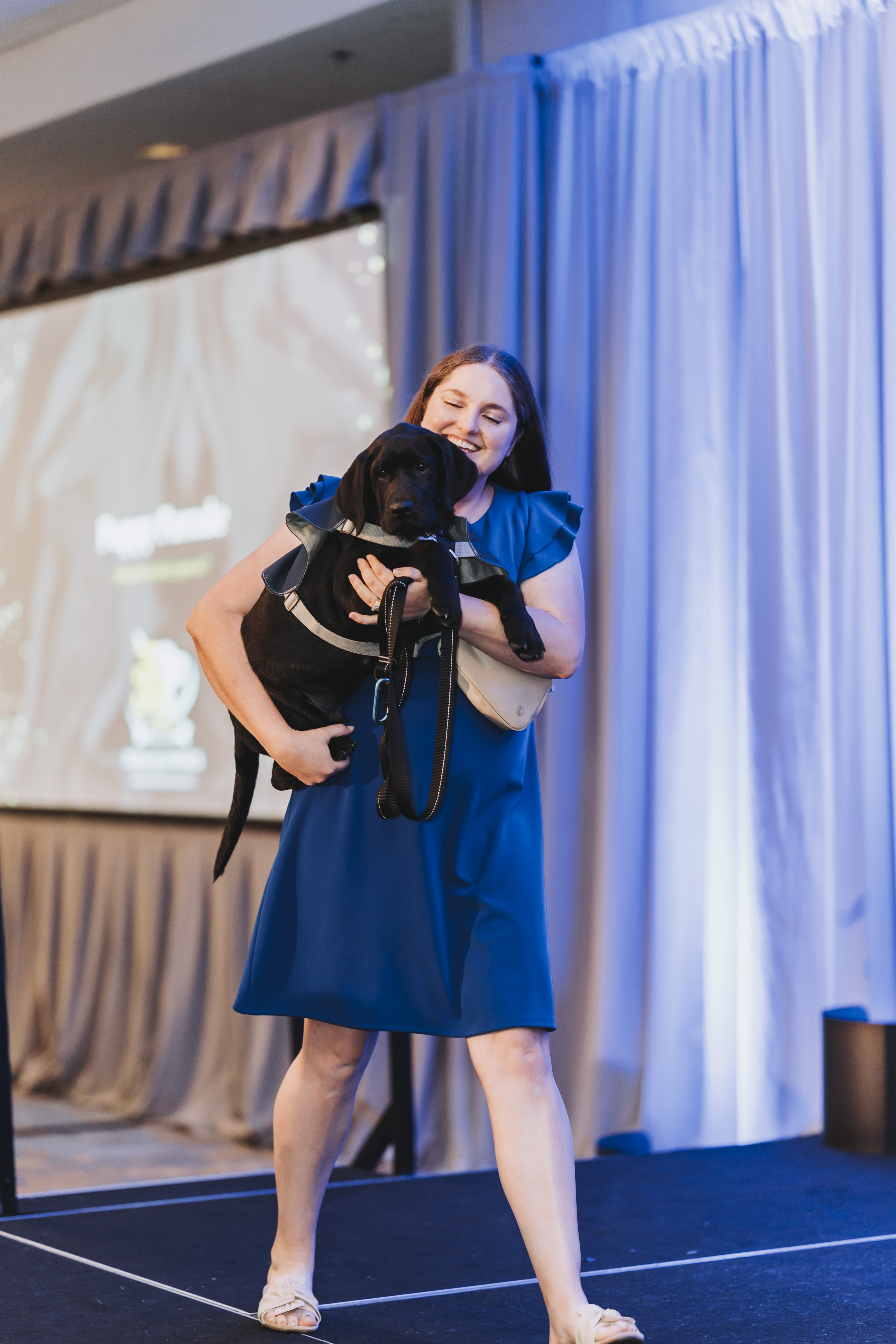 A guest carrying a black puppy during the puppy parade