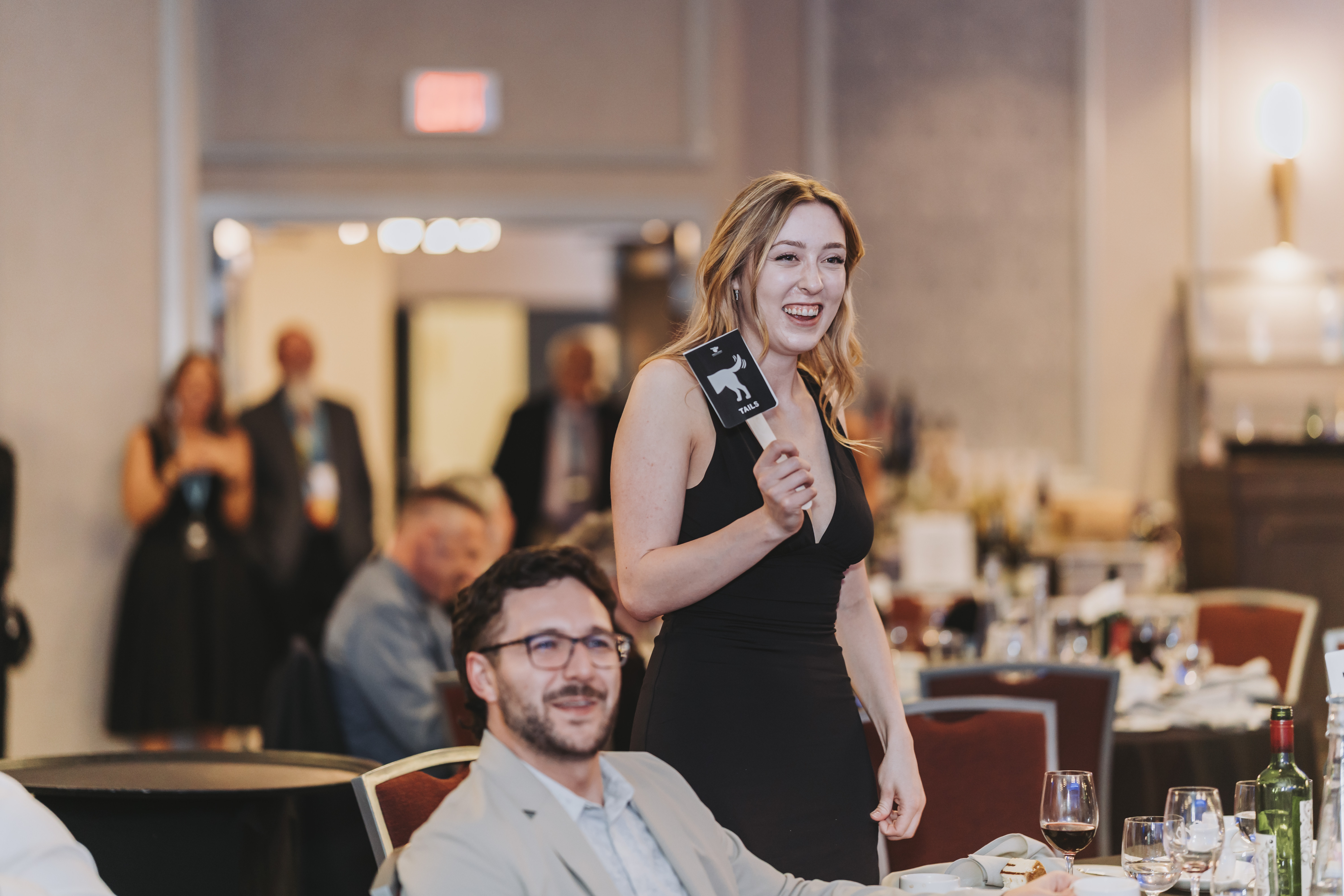 A guest holding up a Tails paddle behind the table