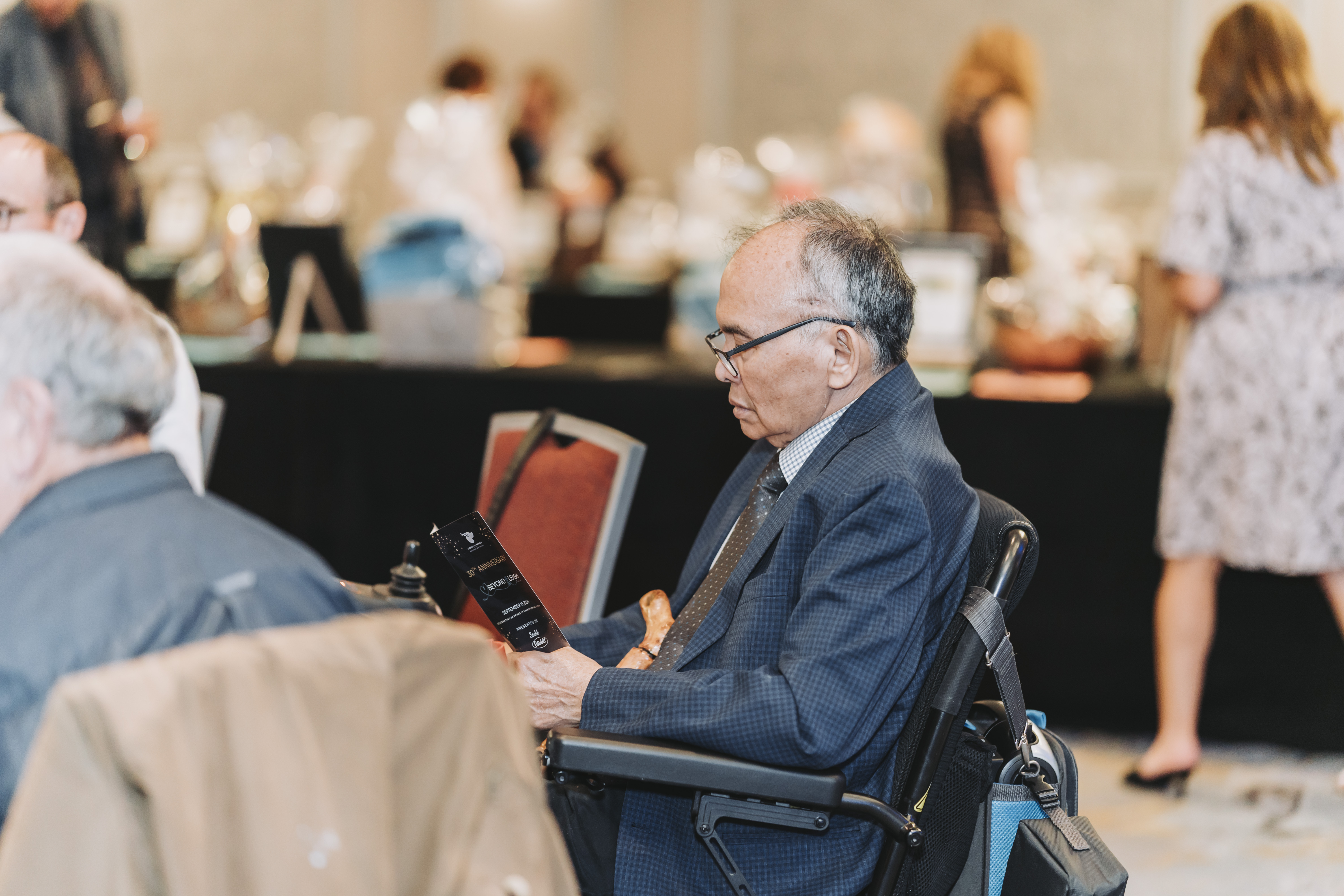 A guest in a wheelchair reading the 30th anniversary gala program