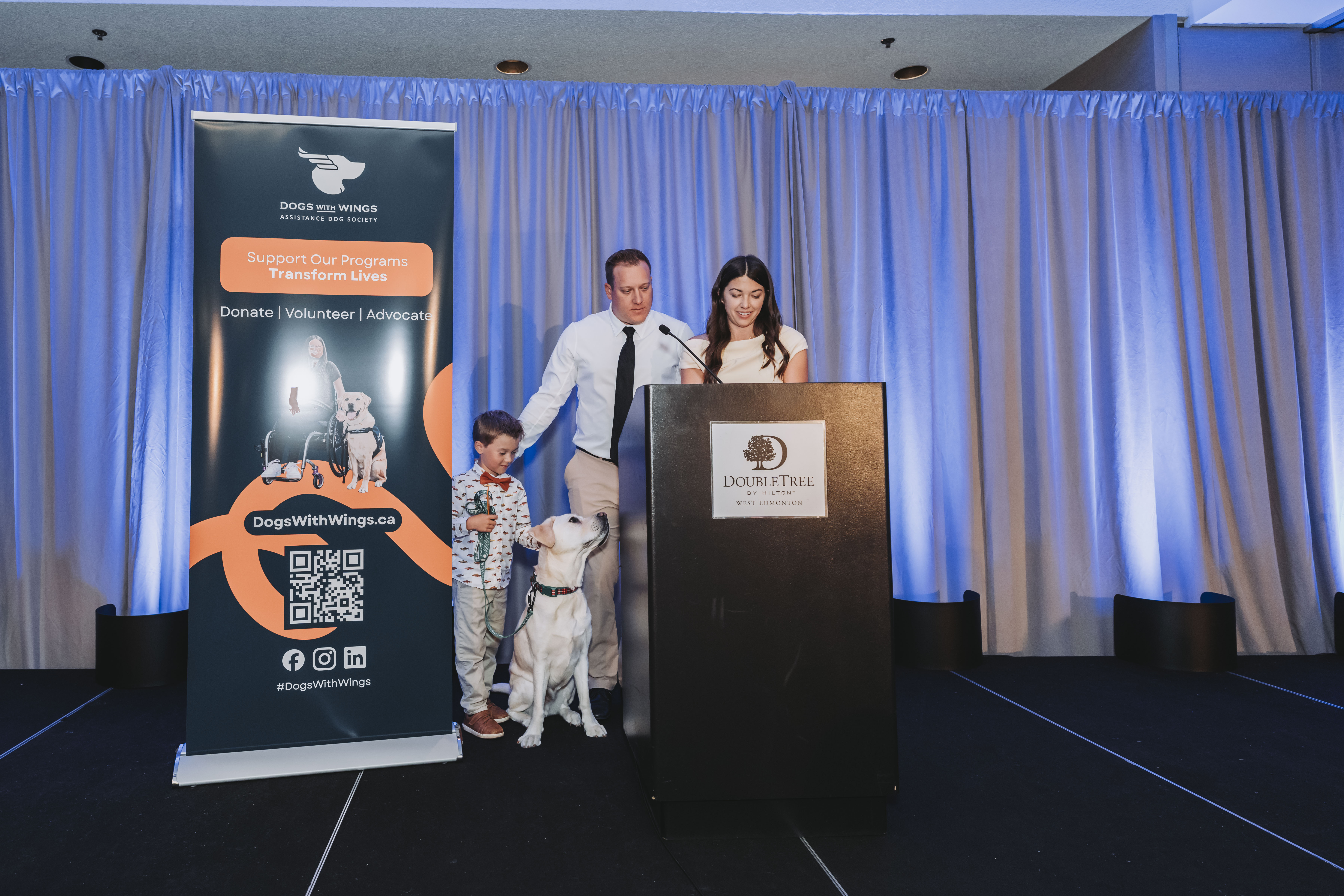 A young guest greeting a service dog on the gala stage