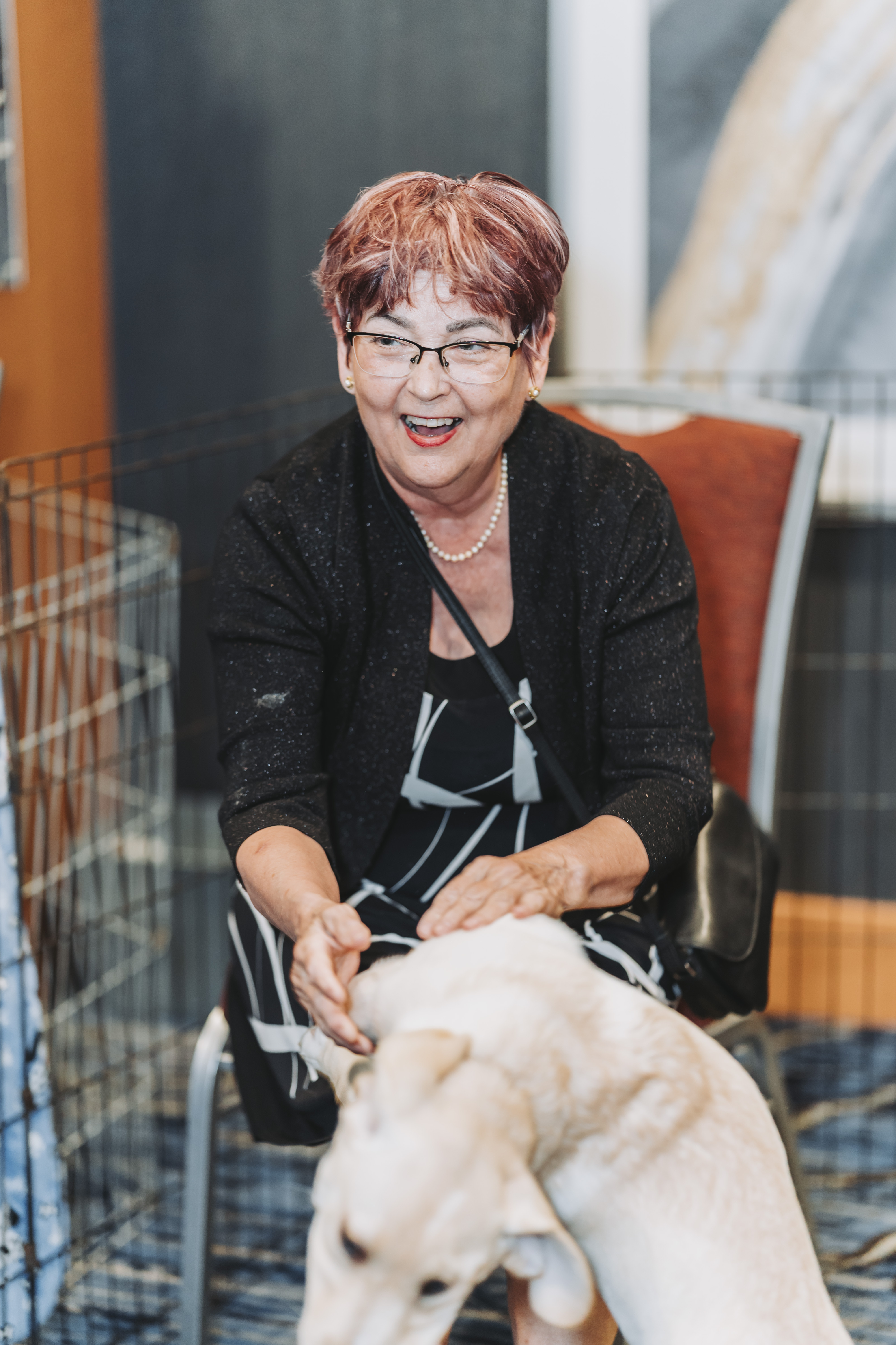 A smiling guest petting a puppy beside the playpen