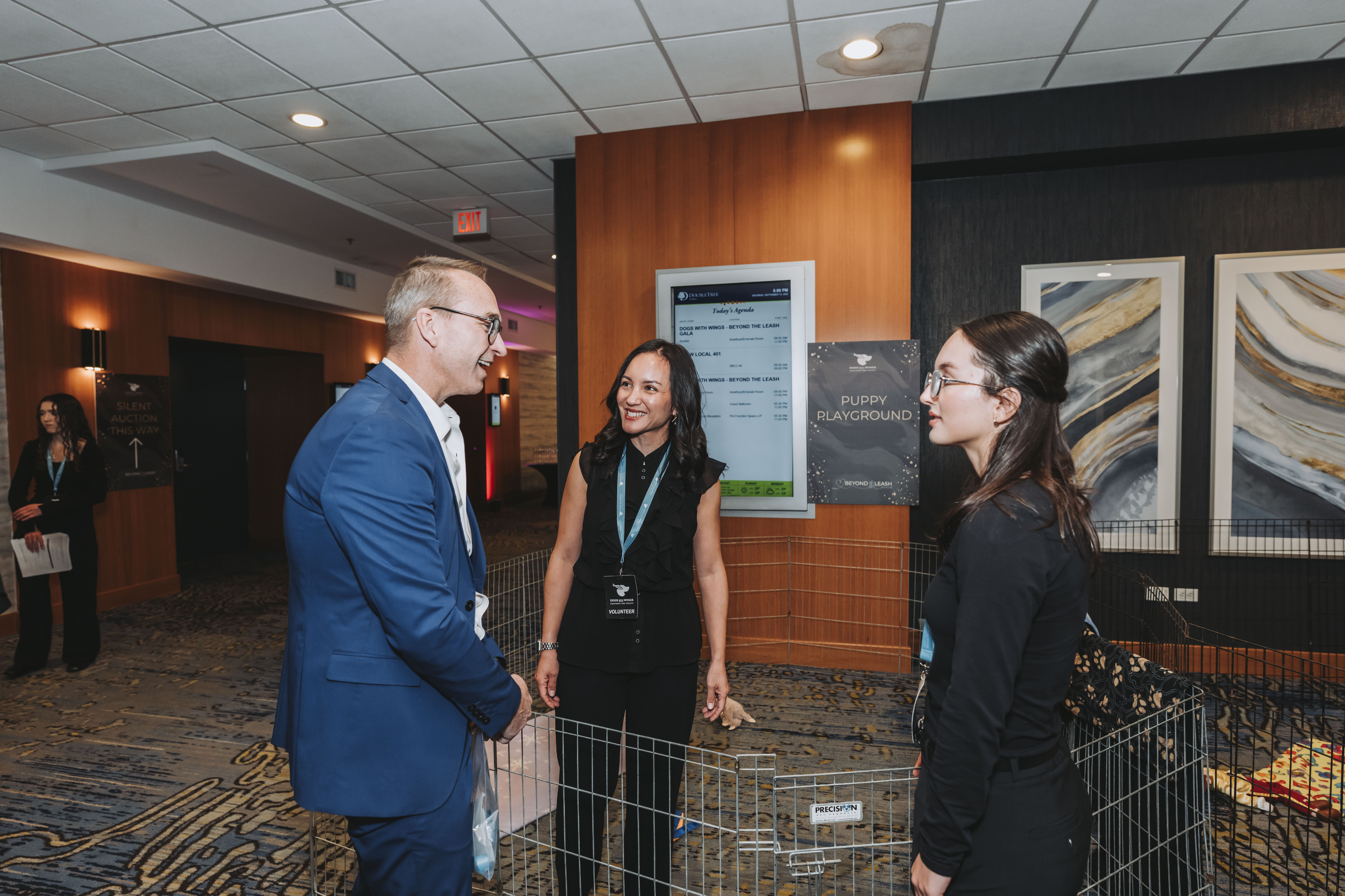 Guests chatting beside the Puppy Playground and the gala agenda screen