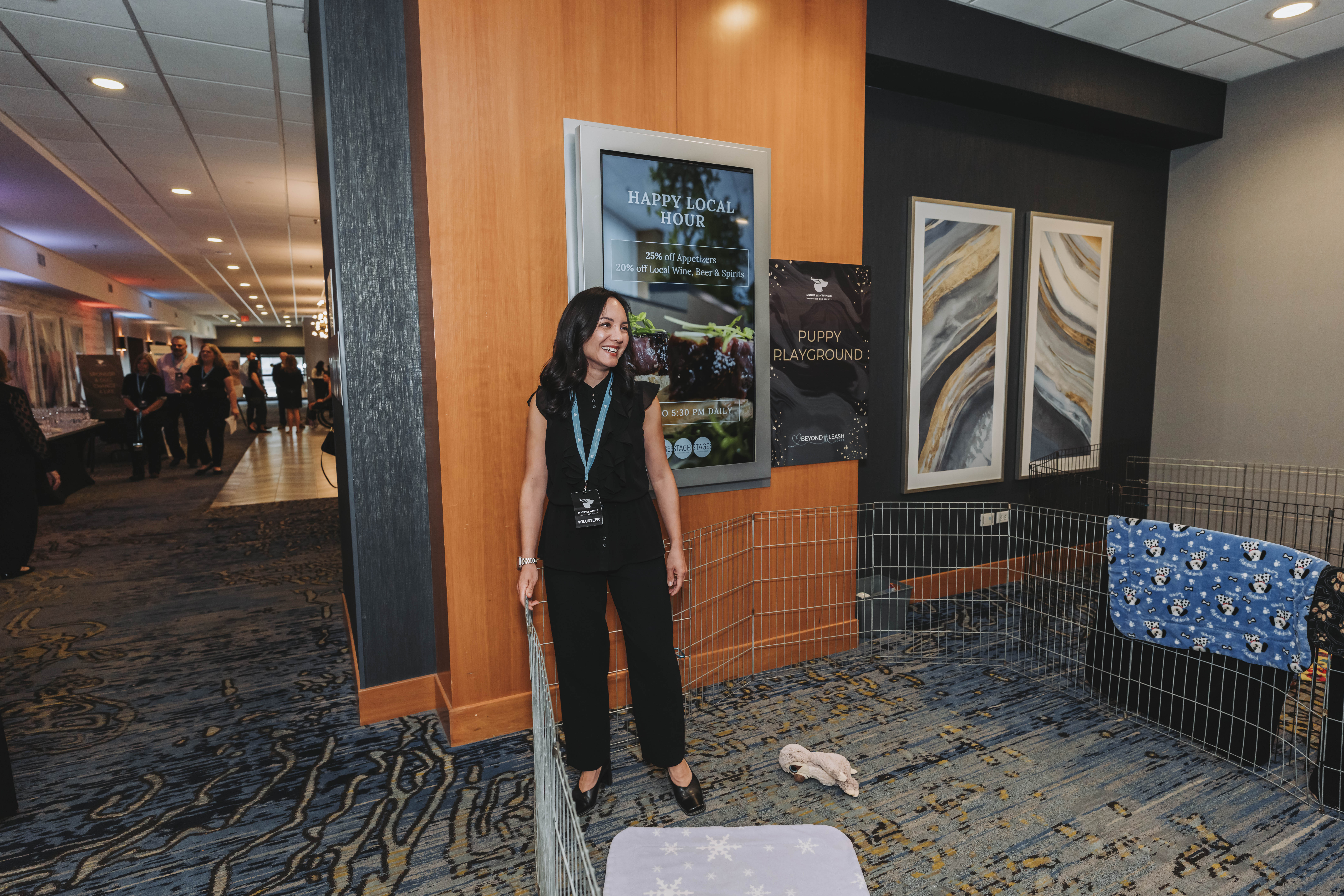A volunteer smiling inside the puppy playground enclosure at the gala