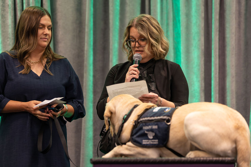 Gala 2025 client sharing story on stage with service dog