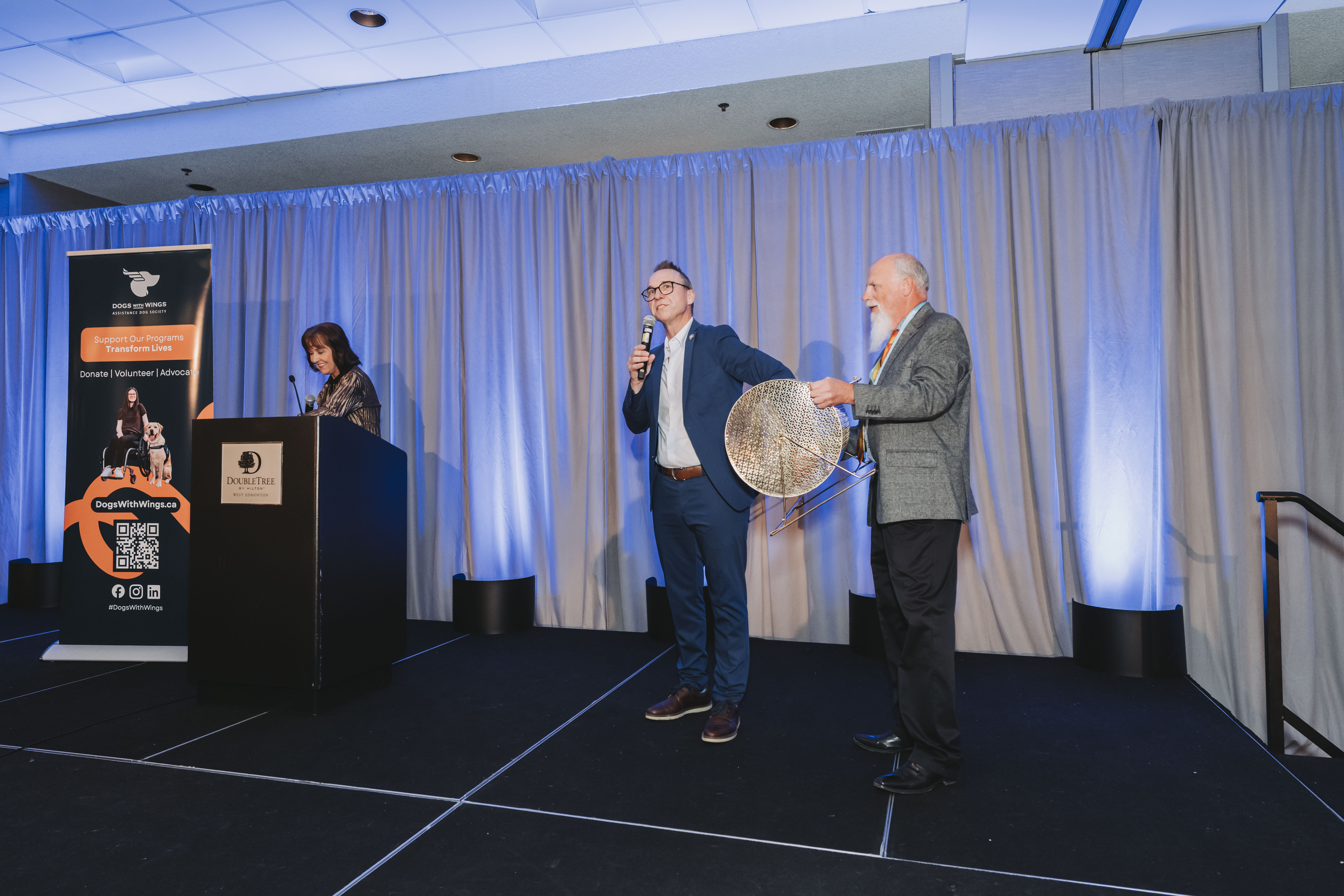 A guest speaking on stage as a raffle drum is brought out