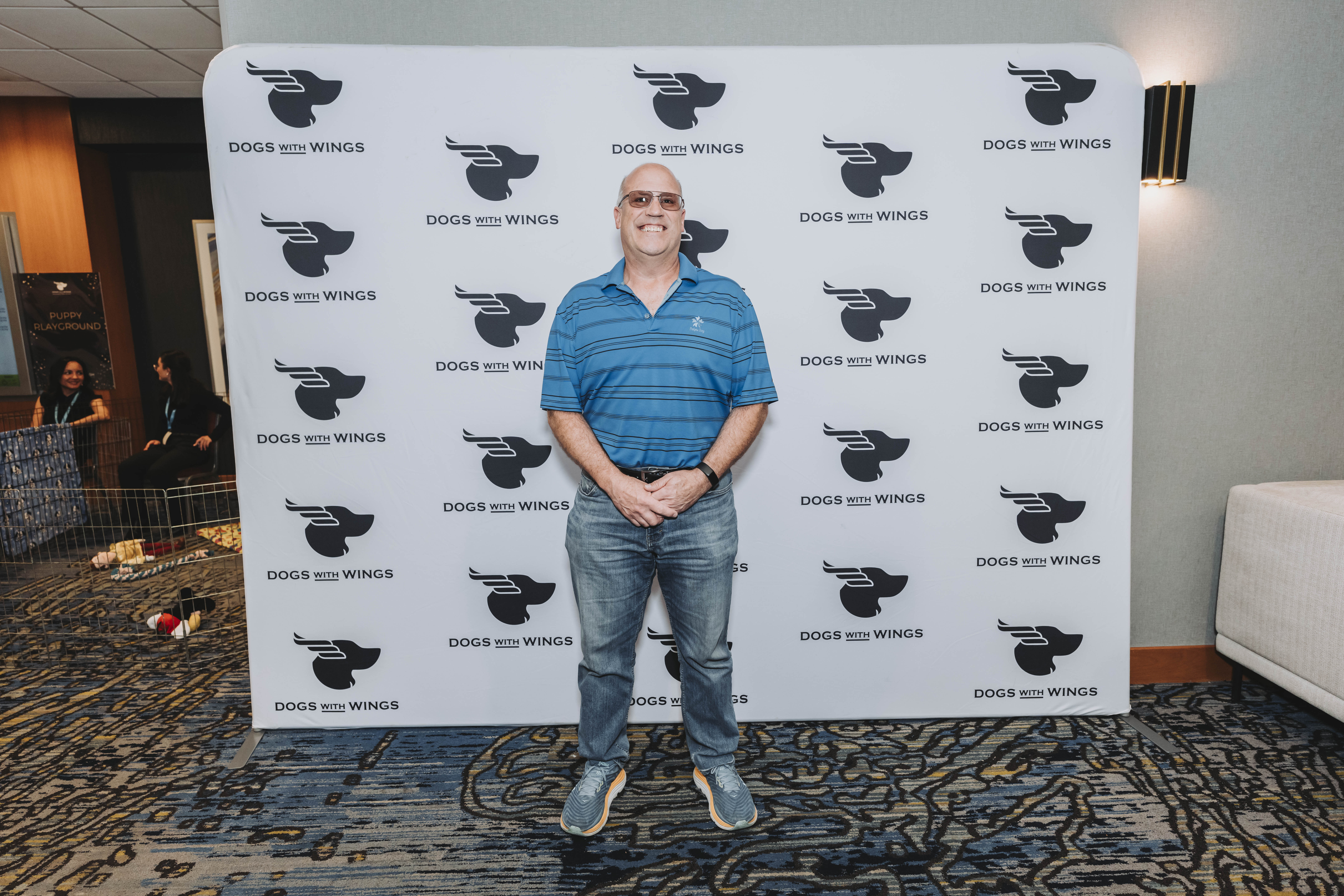 A guest in a striped polo standing at the photo wall