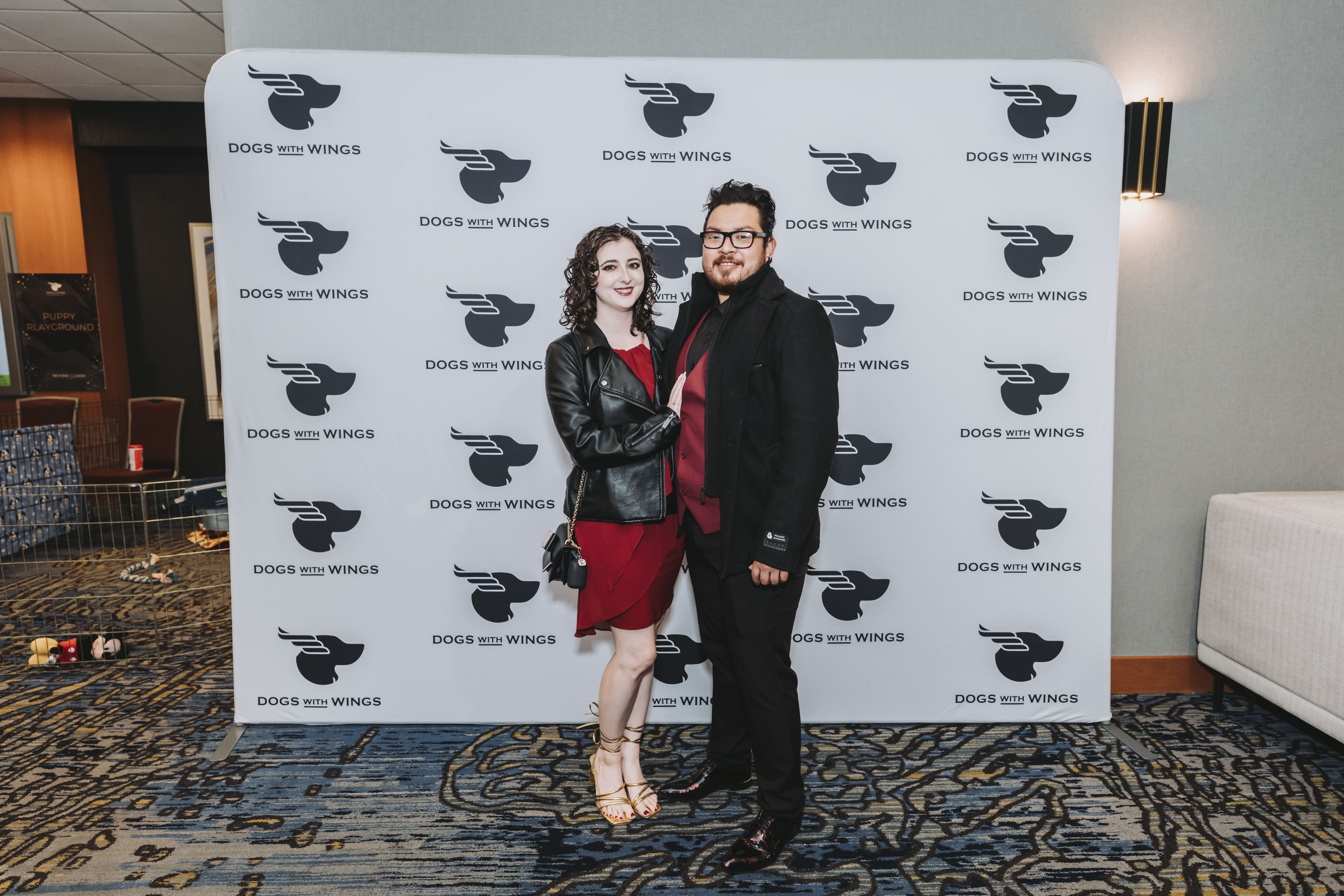 A couple in deep red posing at the gala step-and-repeat