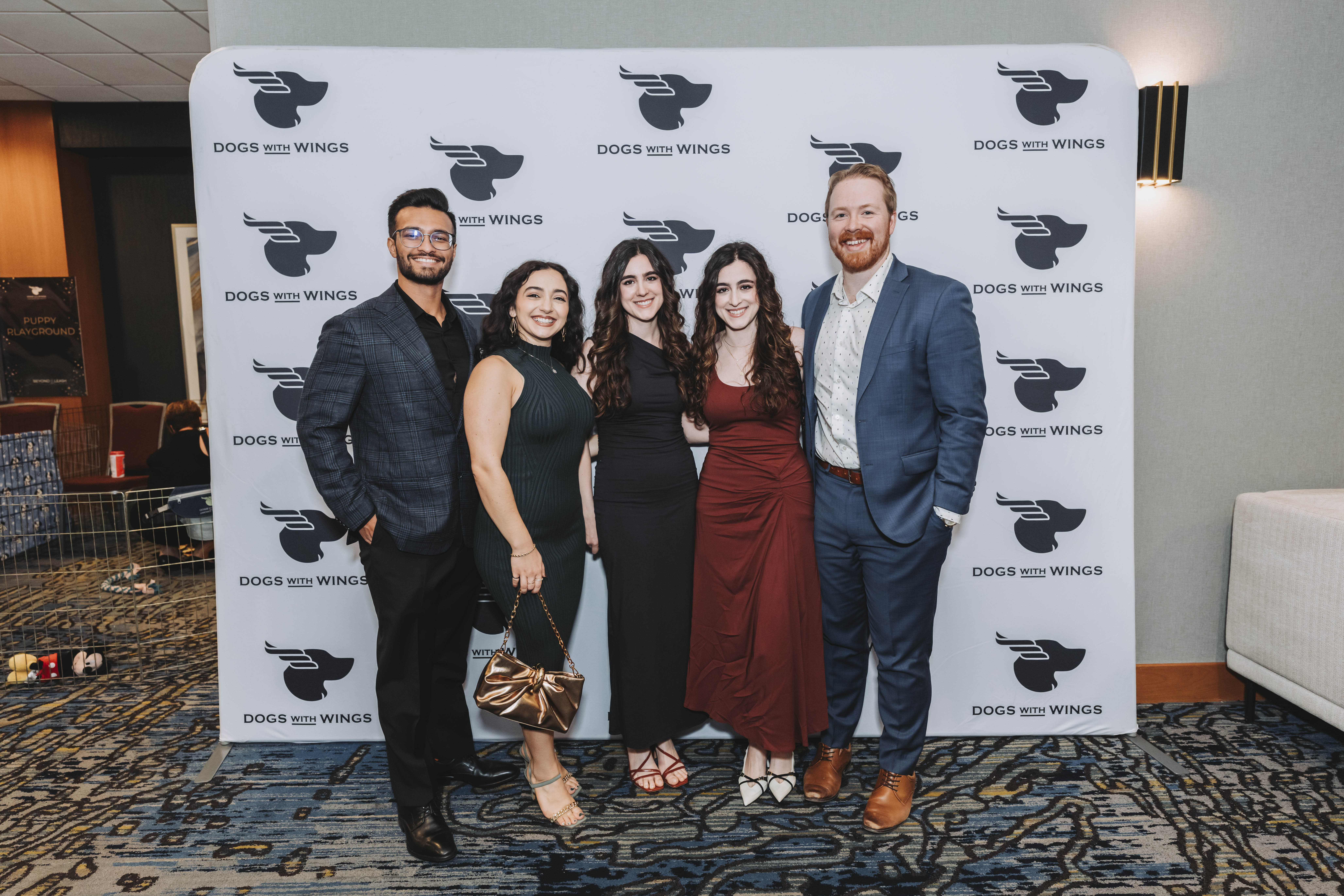 Five guests posing together in front of the backdrop