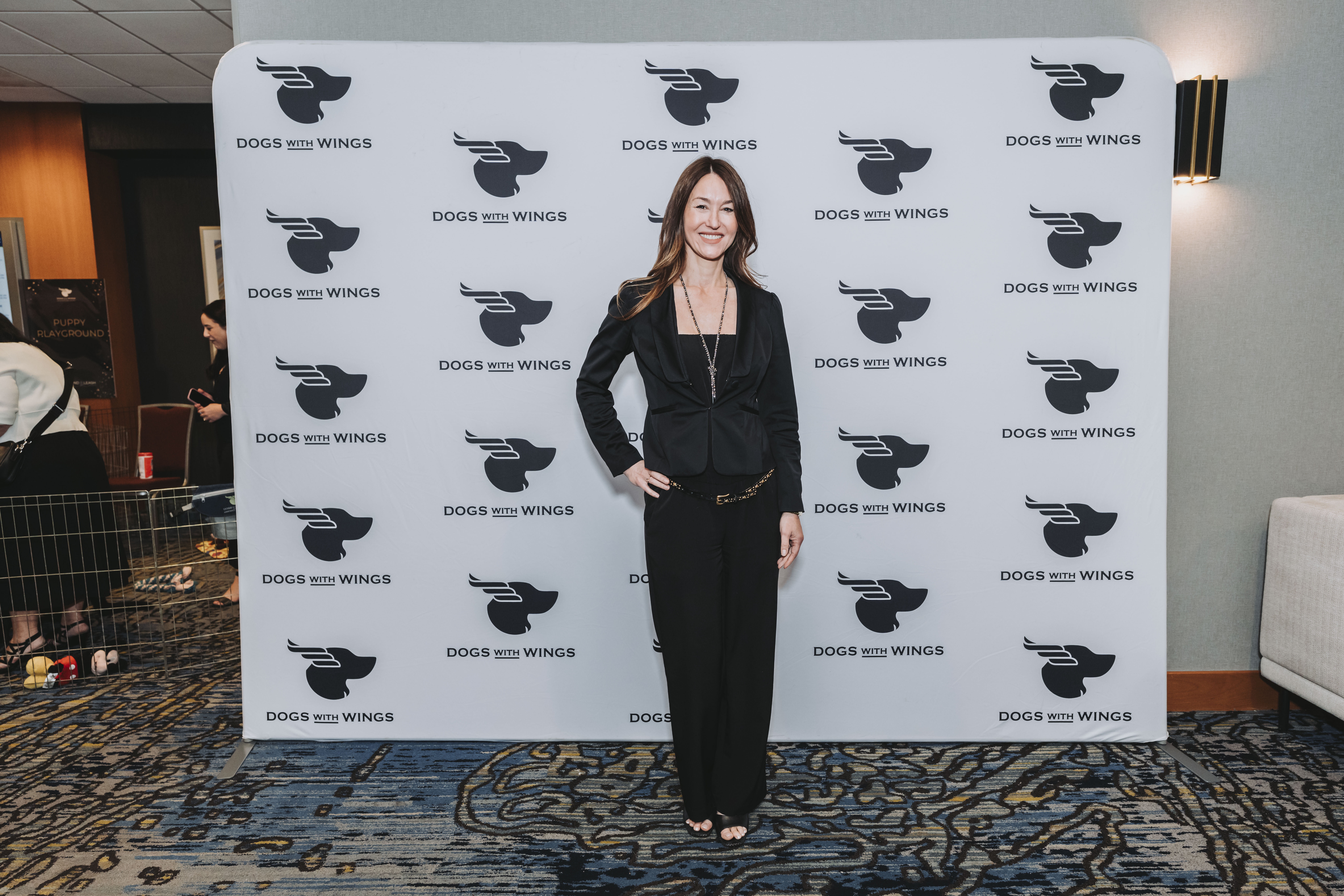 A guest in black posing at the gala step-and-repeat