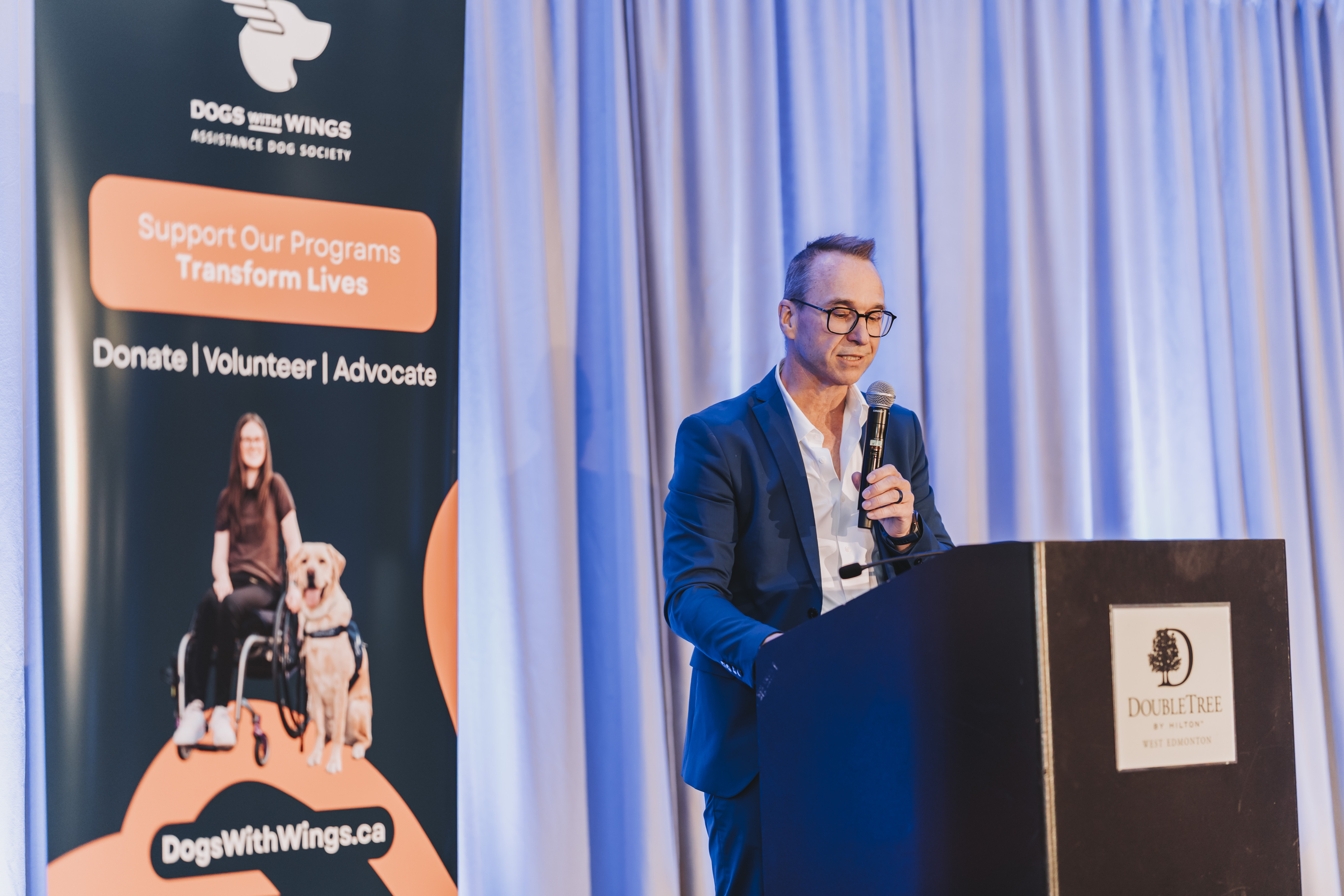 A guest gesturing while speaking at the DoubleTree podium