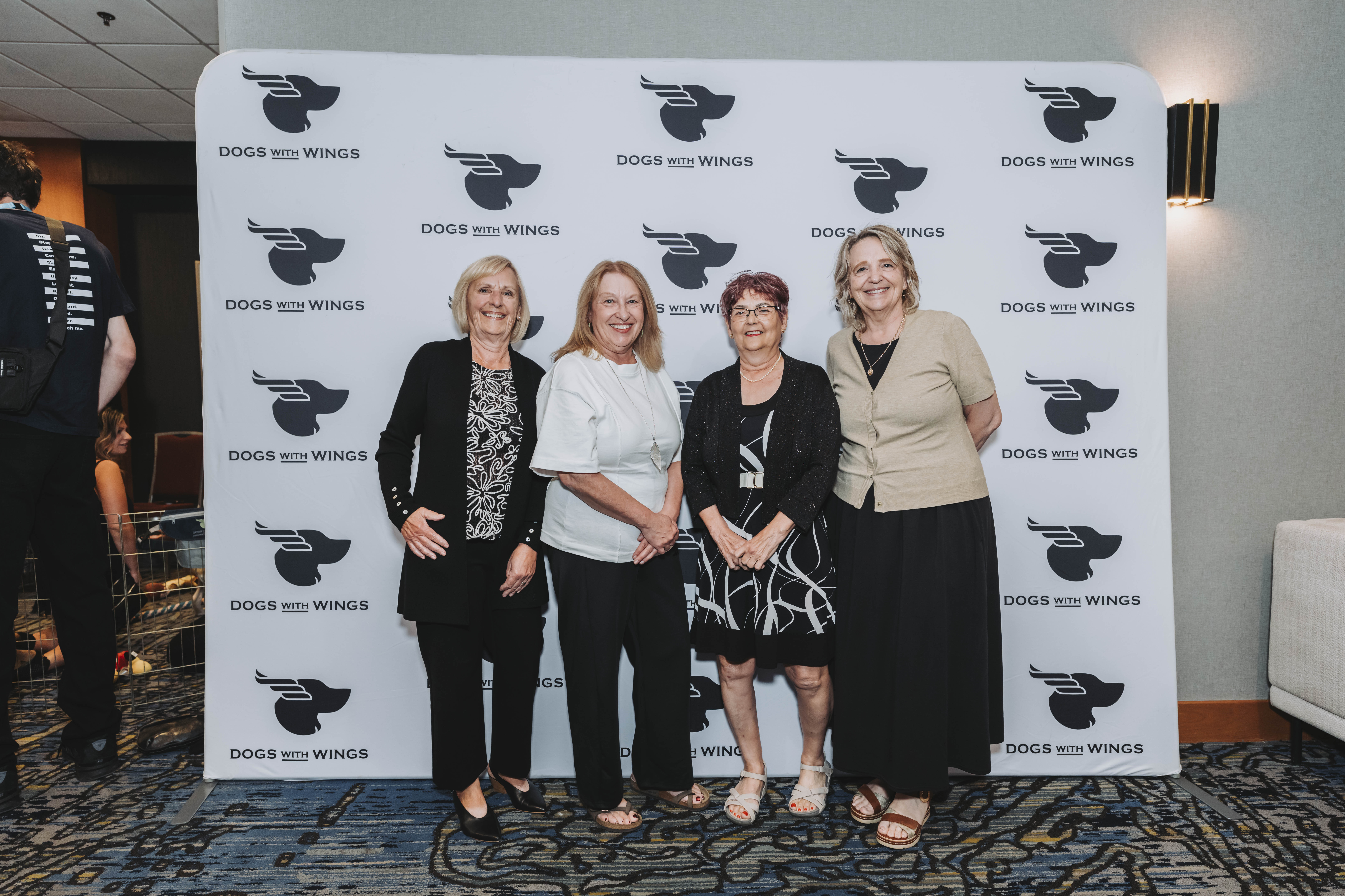 Four guests smiling together at the gala photo wall