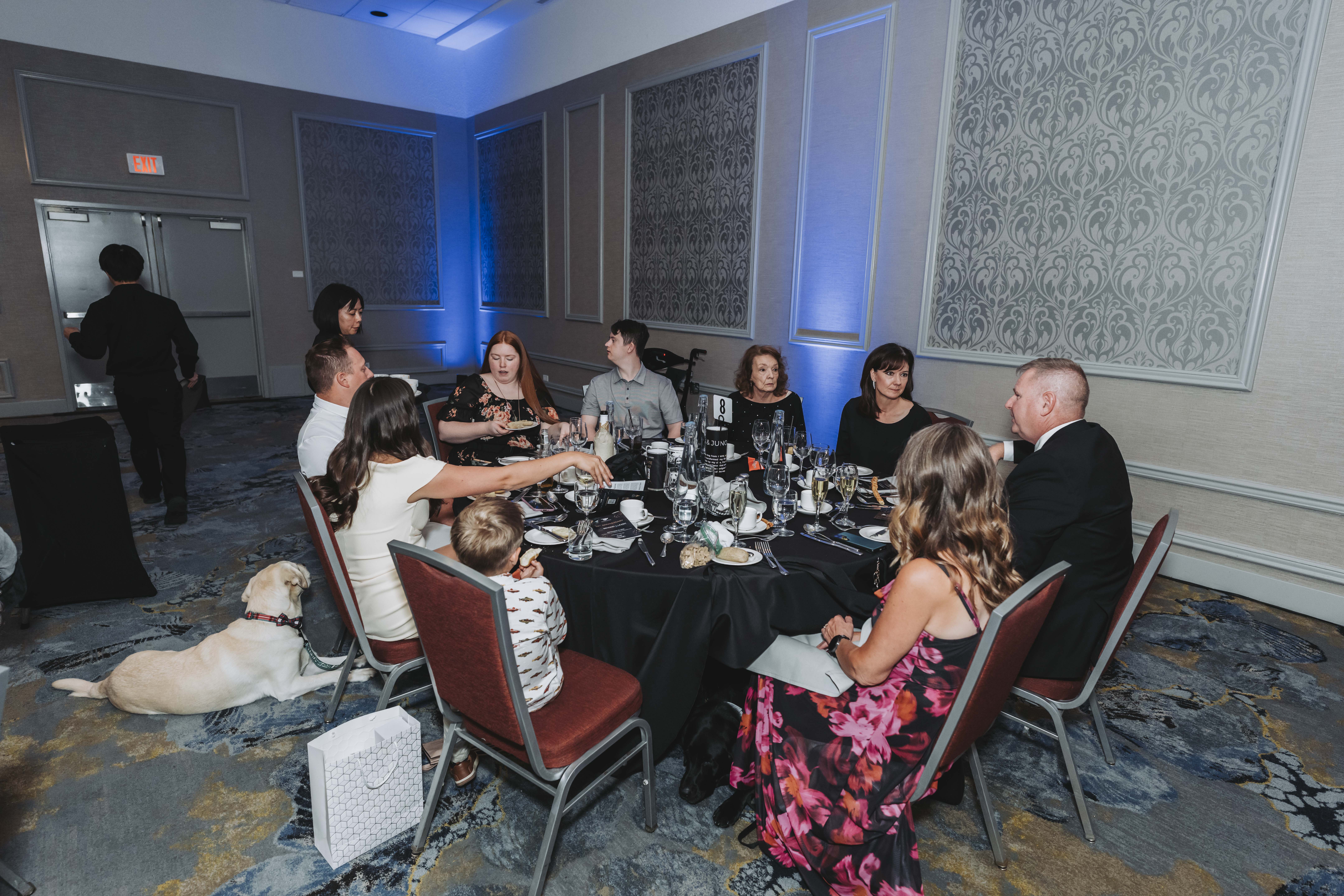 Guests at table eight during dinner, with a yellow Labrador resting nearby