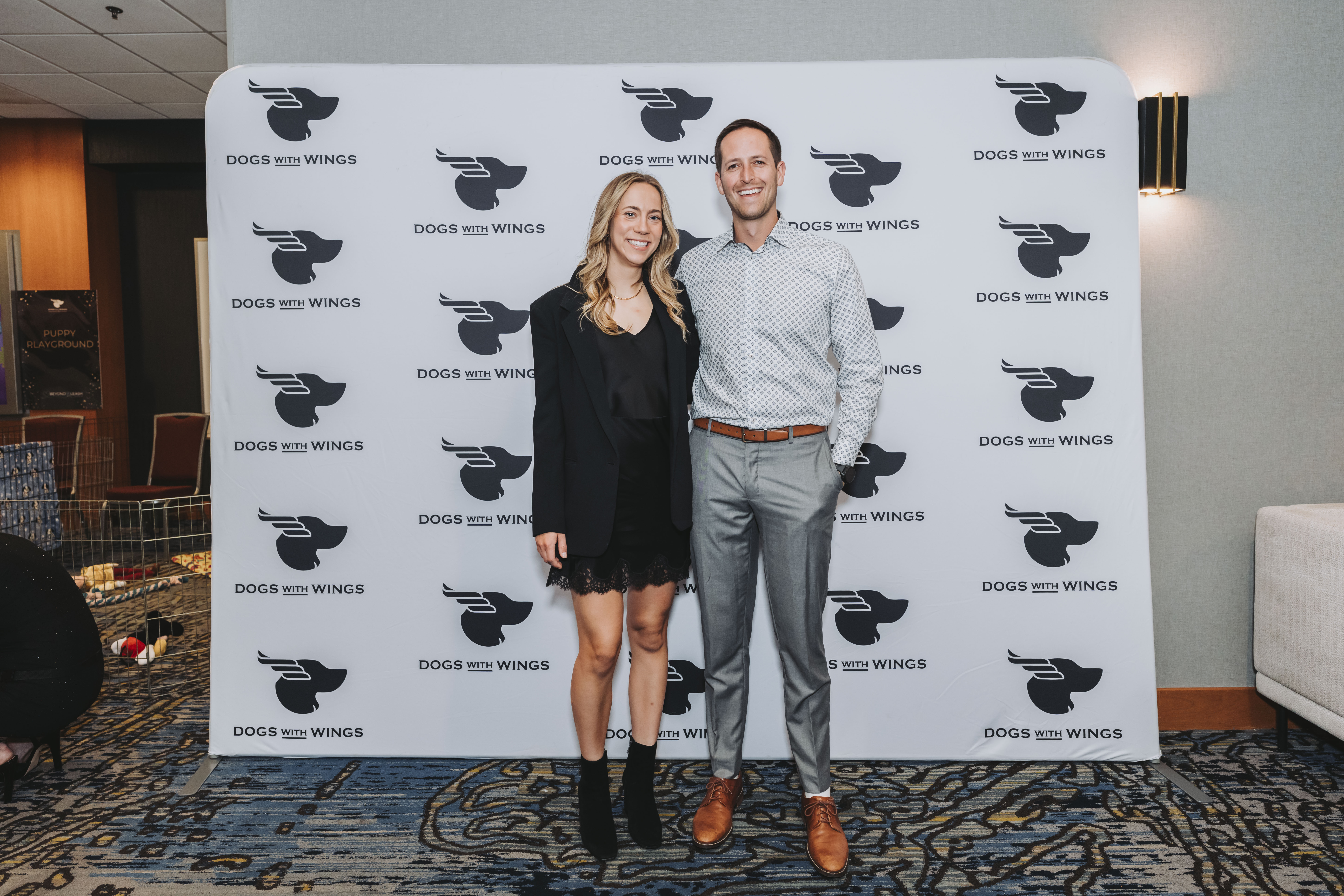 A couple posing at the gala photo wall in black tie