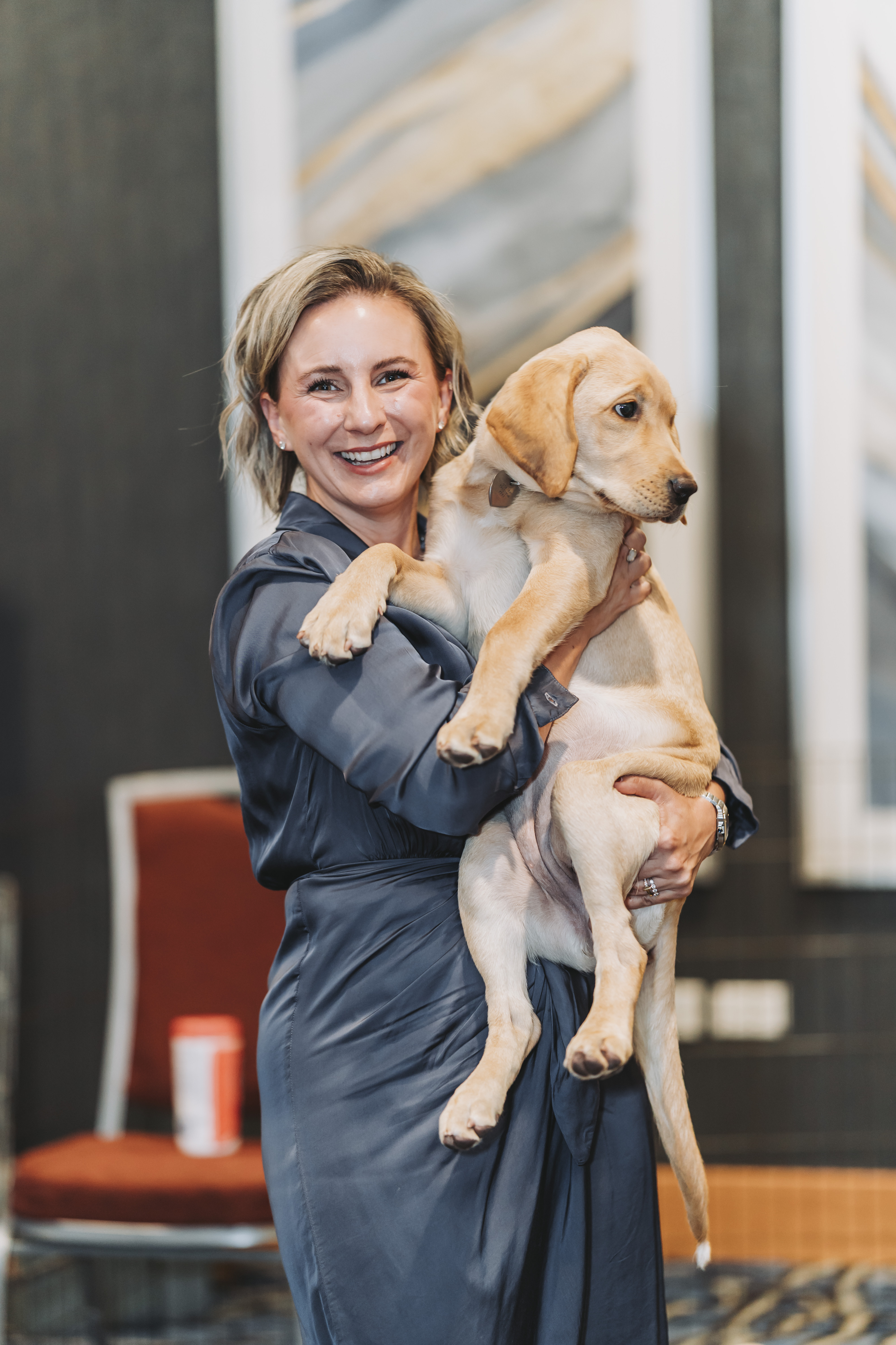 A guest smiling while cradling a yellow Labrador puppy