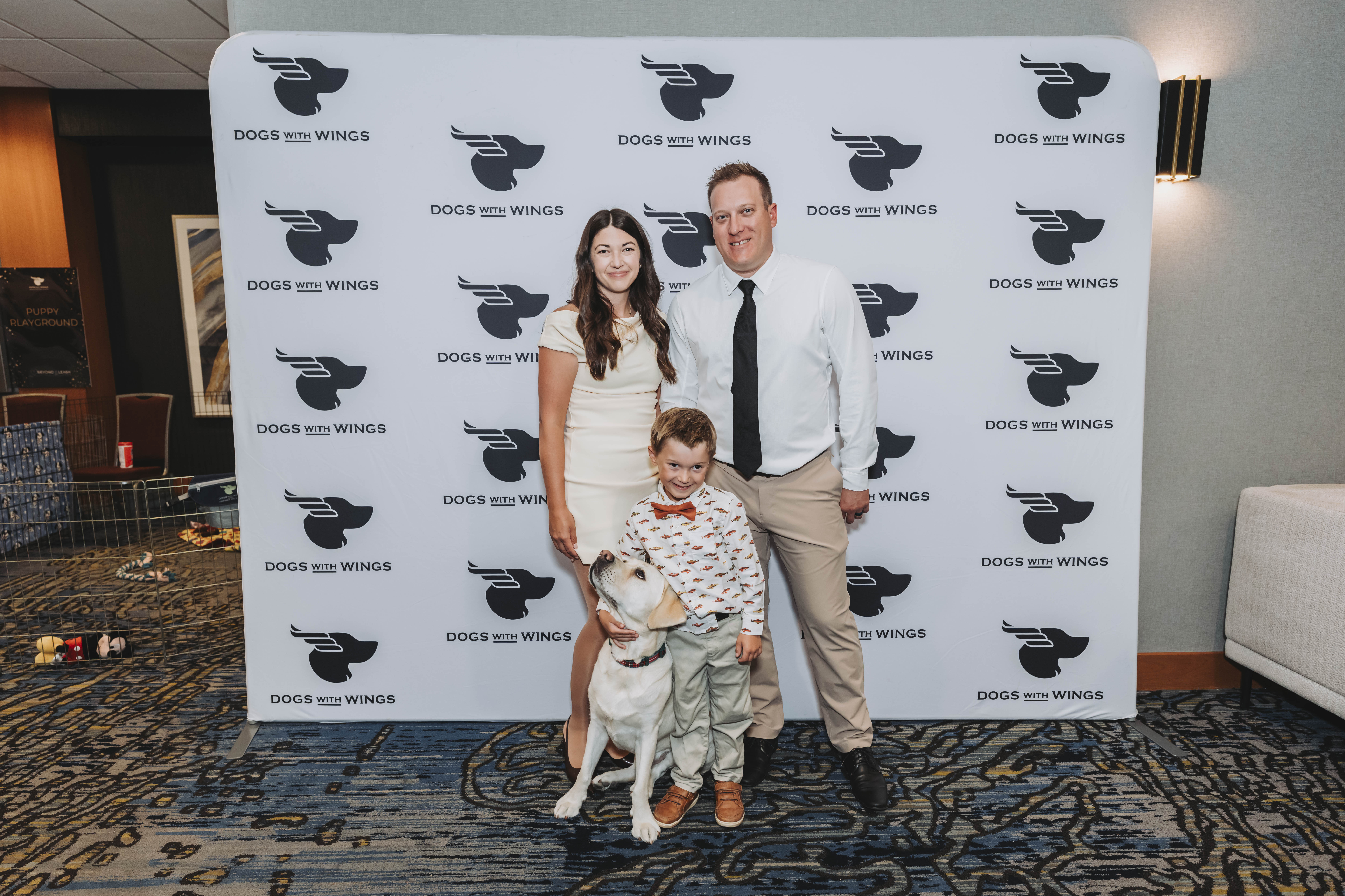 A family with a yellow Labrador posing at the photo wall