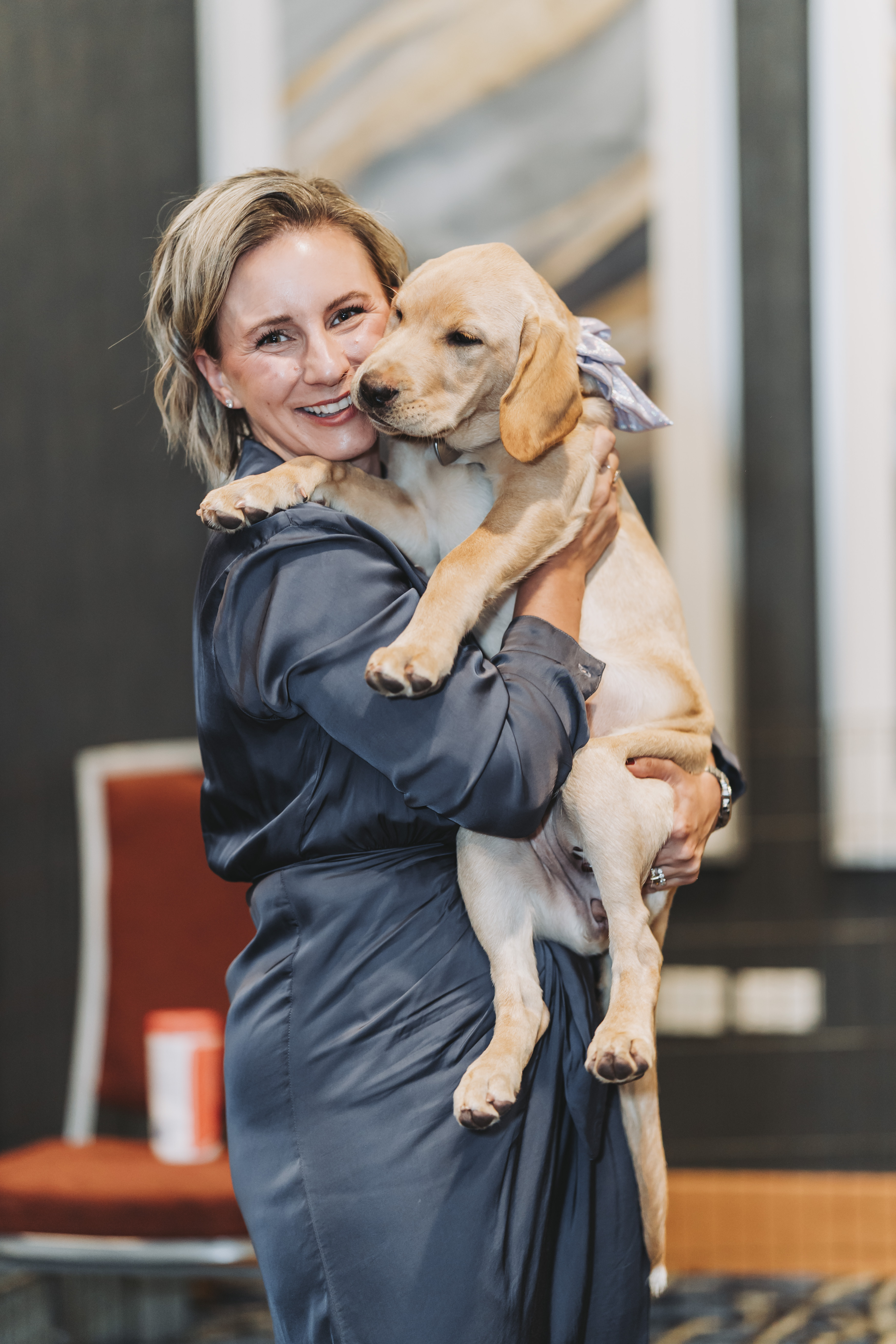 A guest holding a cream Labrador puppy at the gala