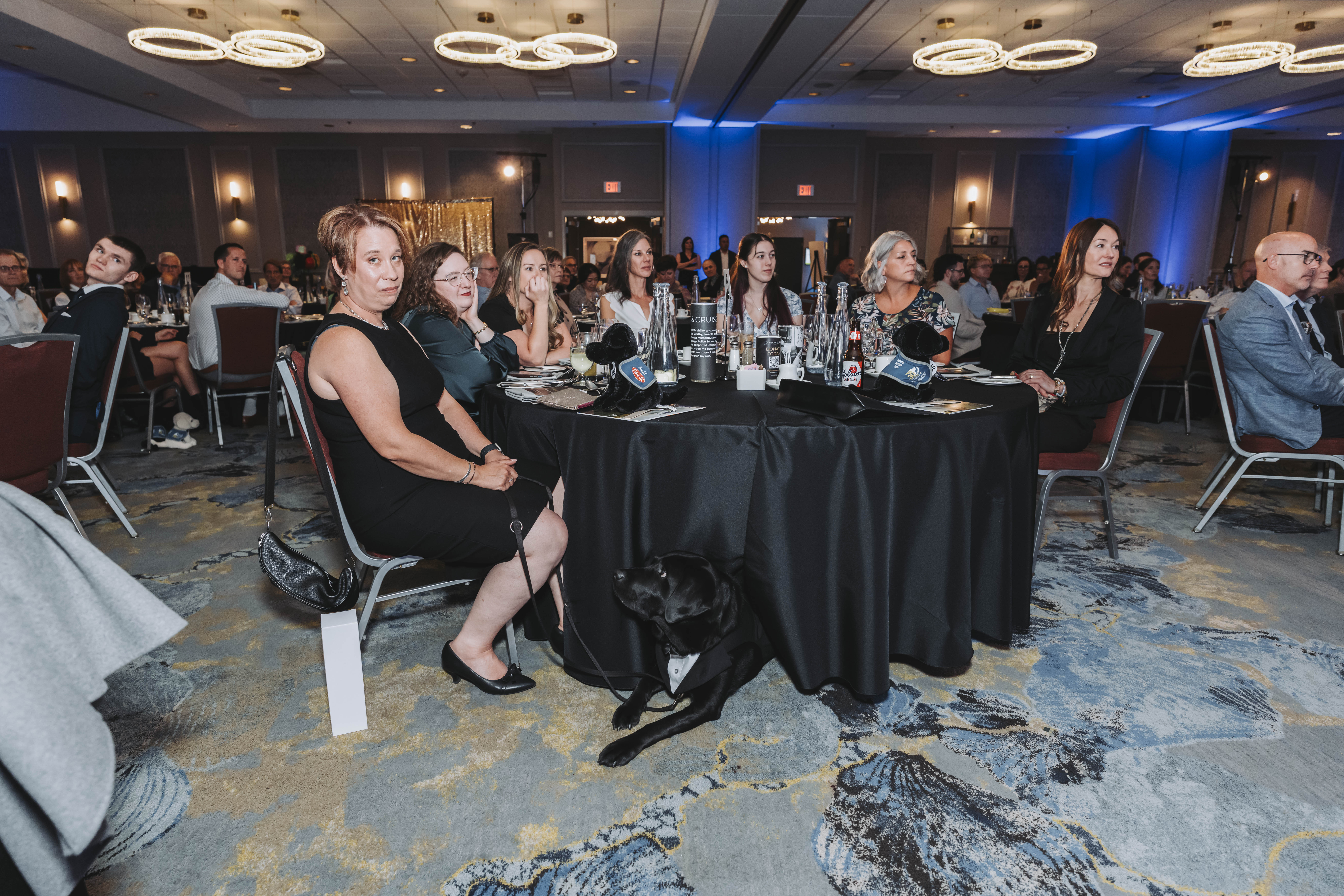 Guests at their table with a black service dog resting beneath