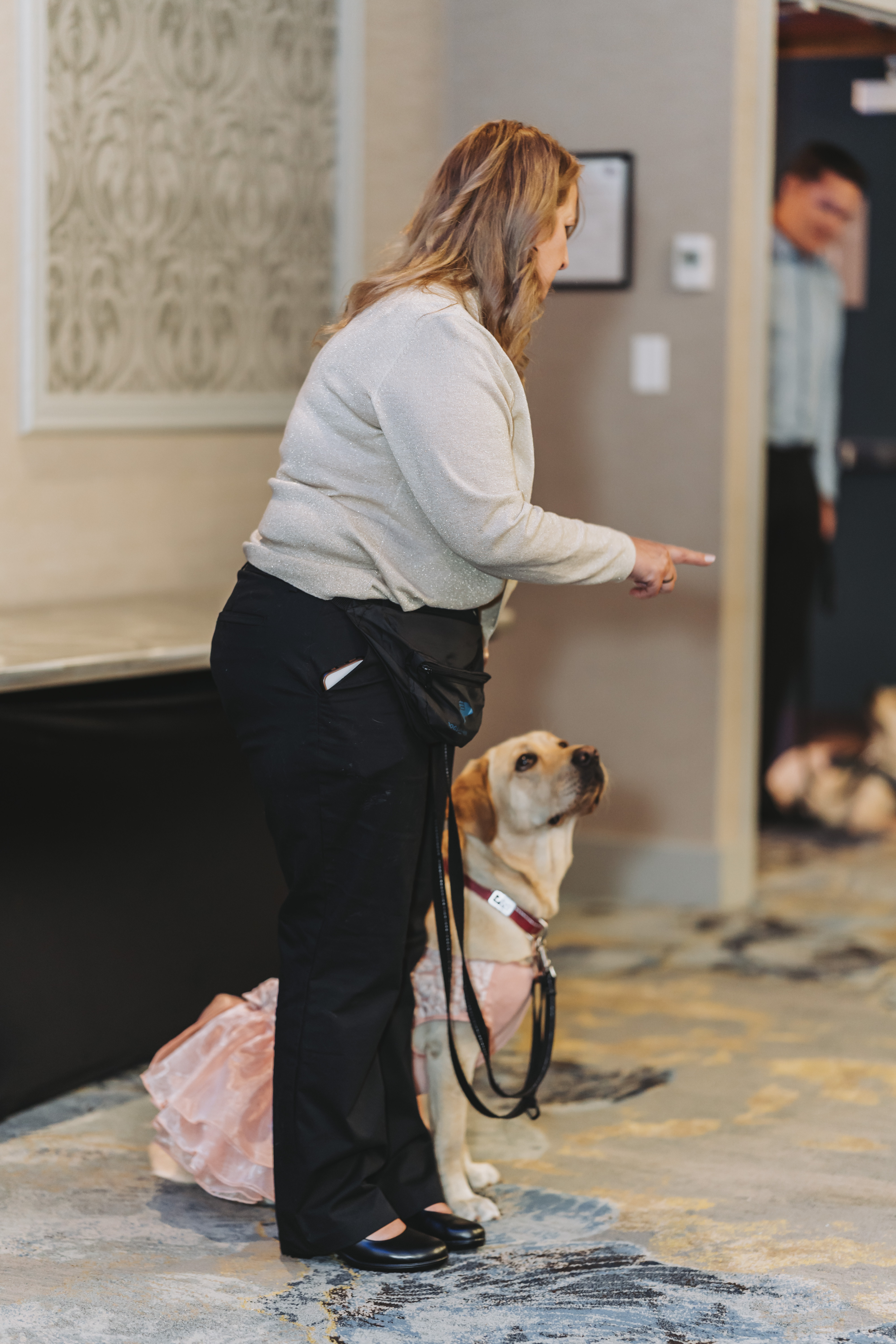 A guest standing with a yellow Labrador in a tutu in the gala hallway